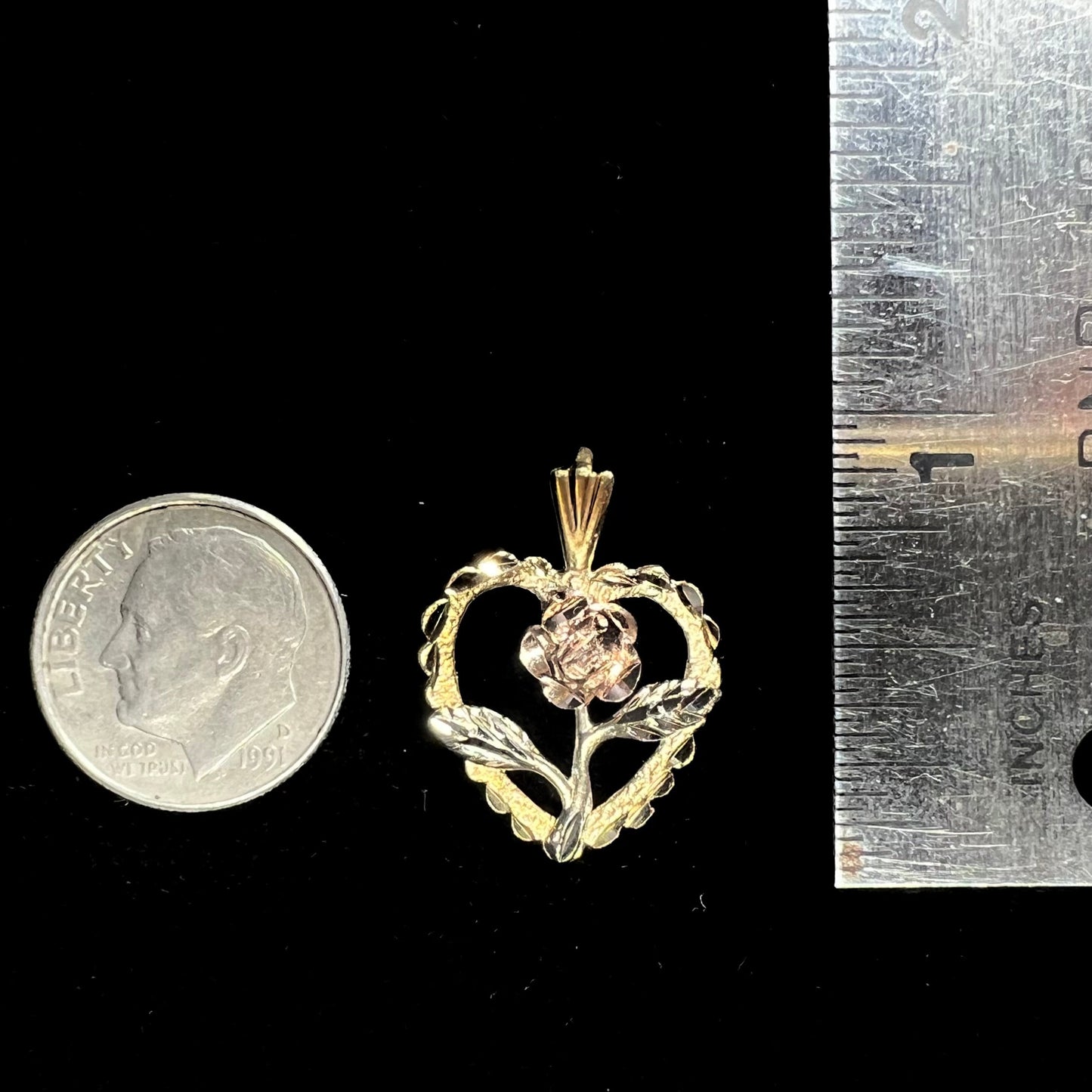 A tricolor gold pendant featuring the design of a heart with a flower in the middle of it.