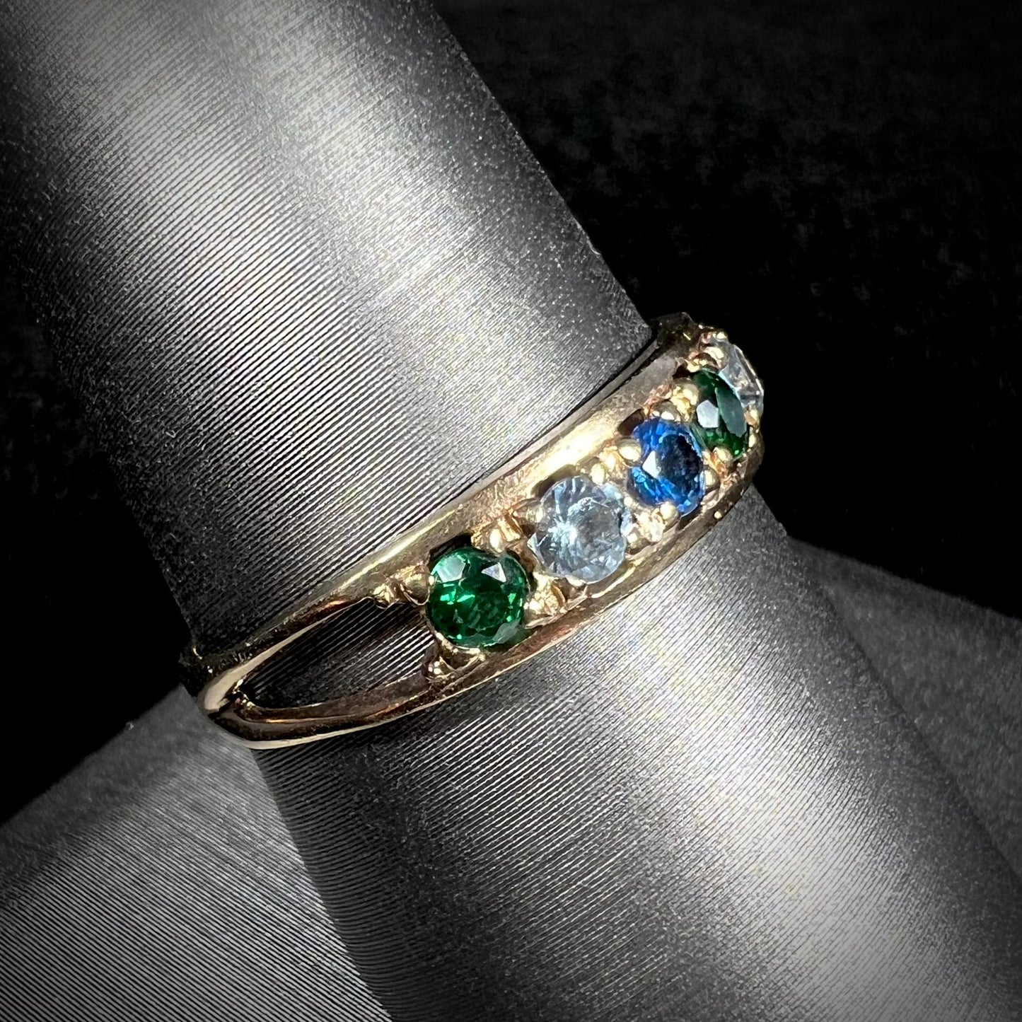 A ladies' yellow gold band set with green, dark blue, light blue, and light purple stones.
