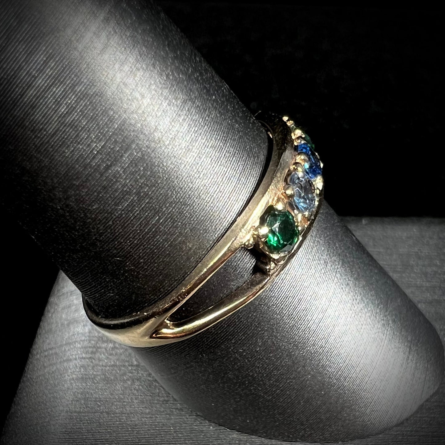 A ladies' yellow gold band set with green, dark blue, light blue, and light purple stones.