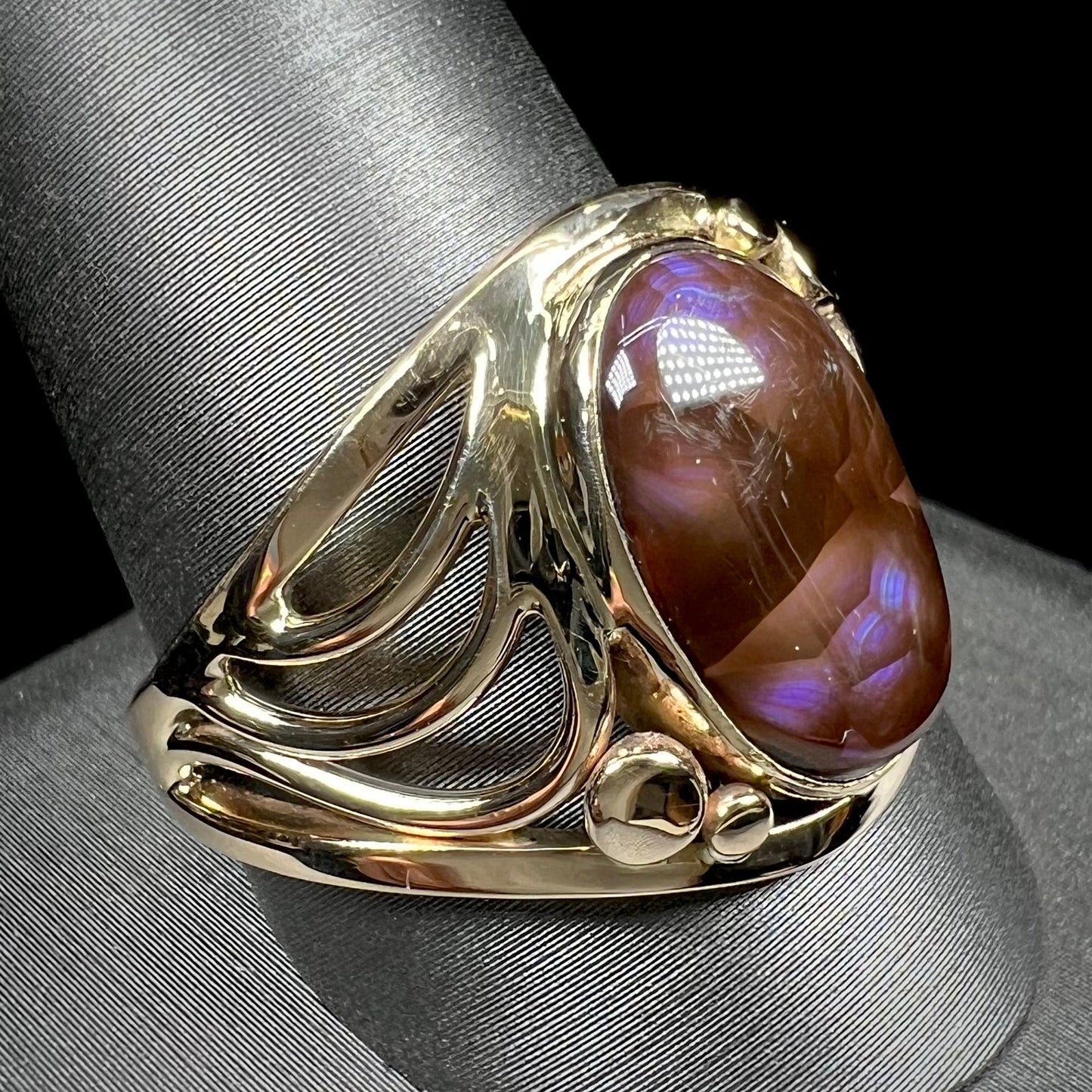 A men's yellow gold fire agate ring. The fire agate is blue and purple with light scratches.