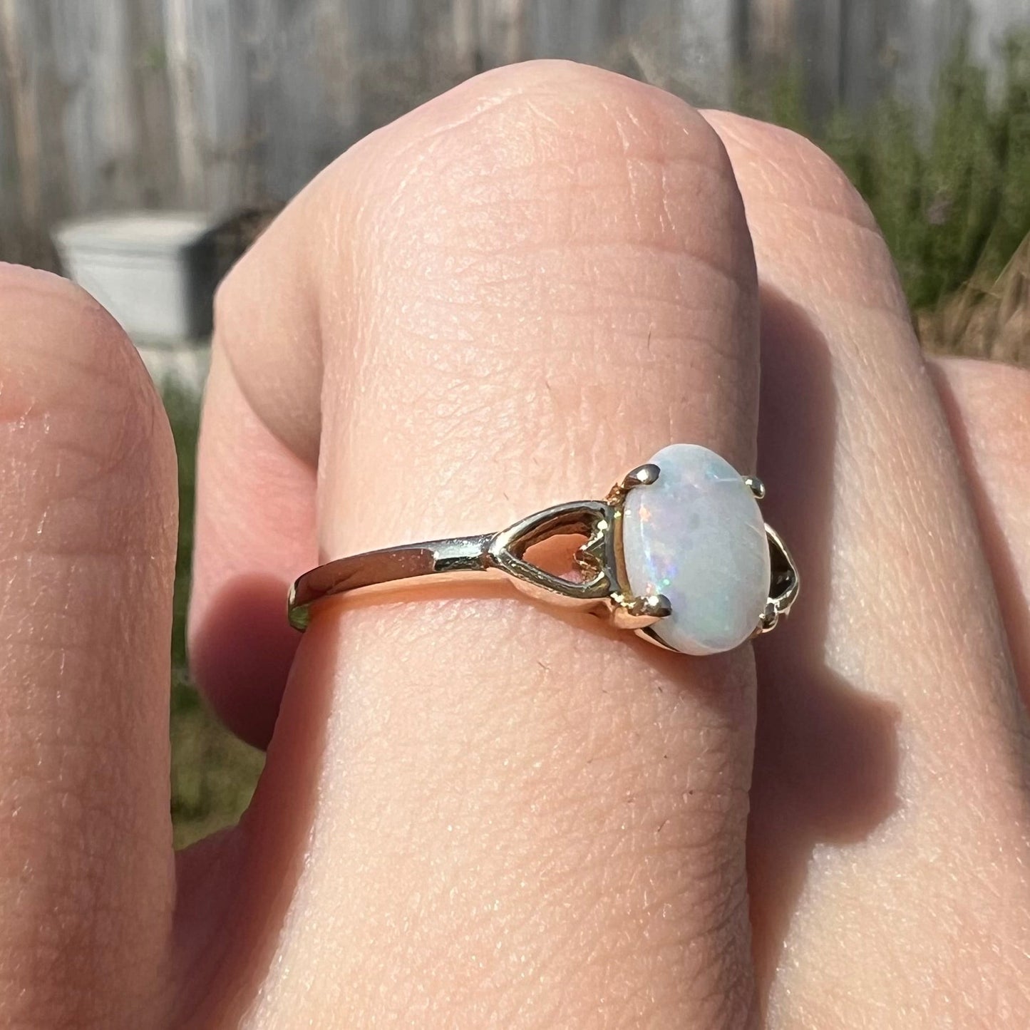 A dainty yellow gold ring mounted with a vivdly bright red Australian opal. The ring has two heart shaped designs.