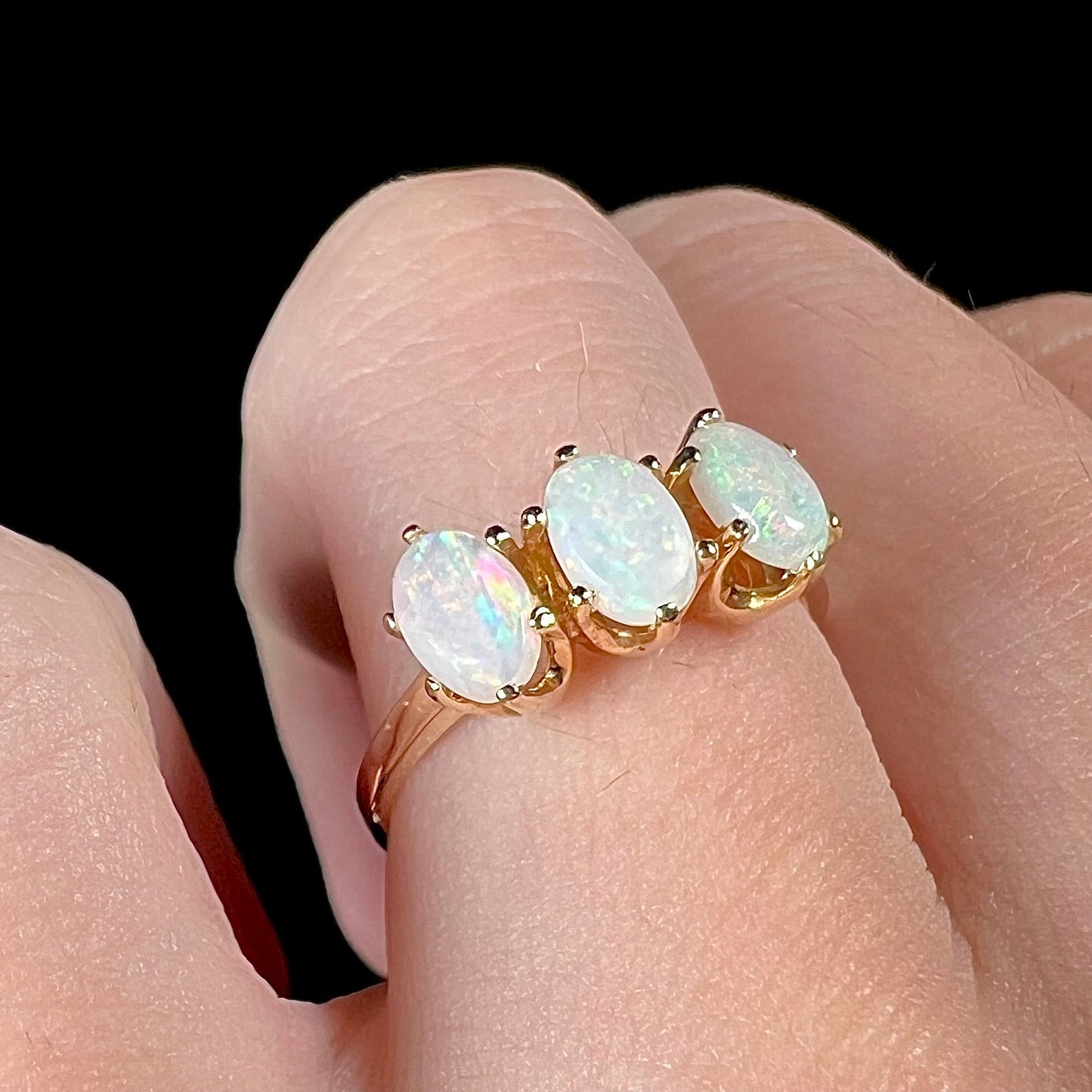 A vintage yellow gold ring mounted with three oval cut white Australian opals.