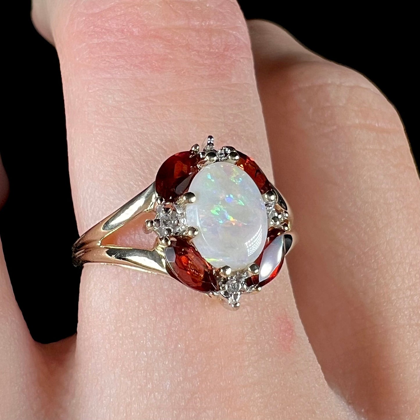 A ladies natural opal ring in yellow gold. The opal is surrounded by red marquise cut garnets and diamonds.