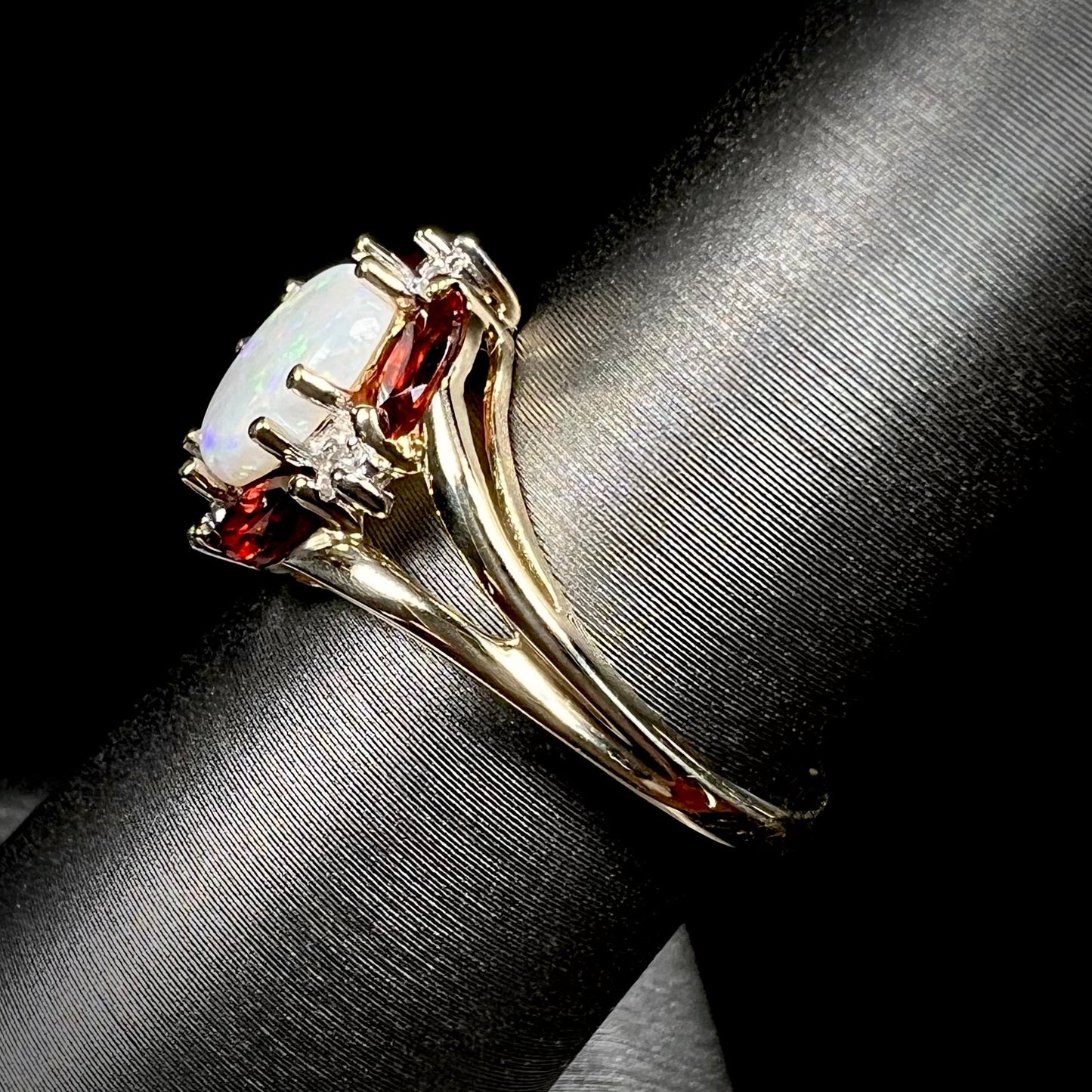 A ladies natural opal ring in yellow gold. The opal is surrounded by red marquise cut garnets and diamonds.