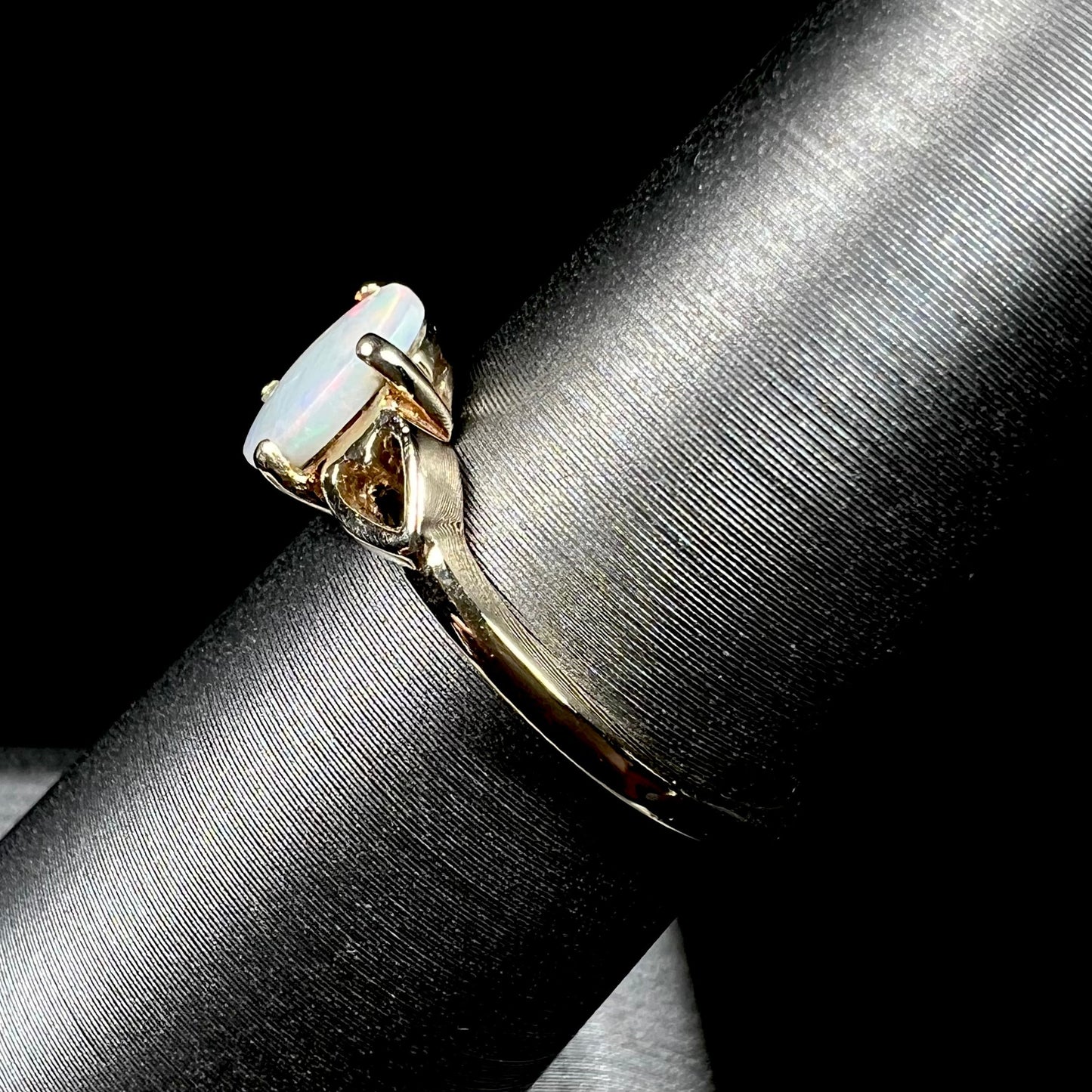 A dainty yellow gold ring mounted with a vivdly bright red Australian opal. The ring has two heart shaped designs.