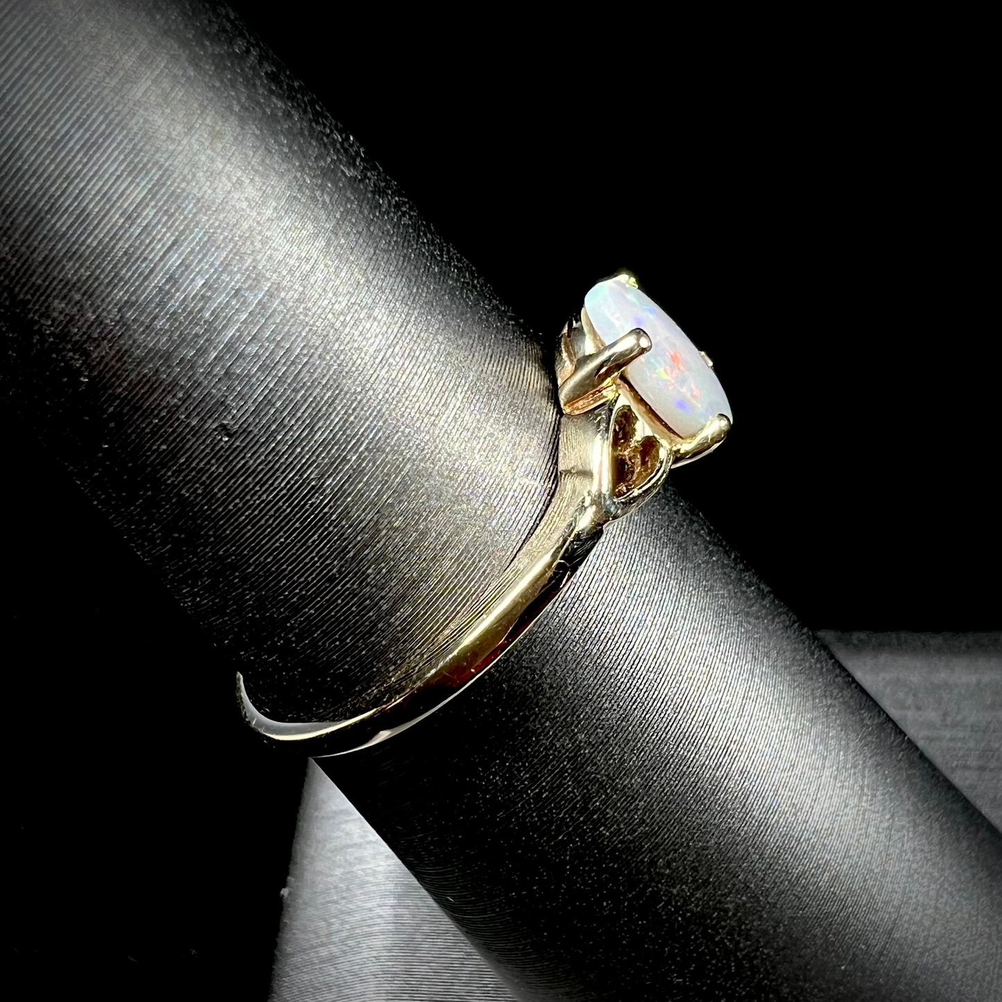 A dainty yellow gold ring mounted with a vivdly bright red Australian opal. The ring has two heart shaped designs.