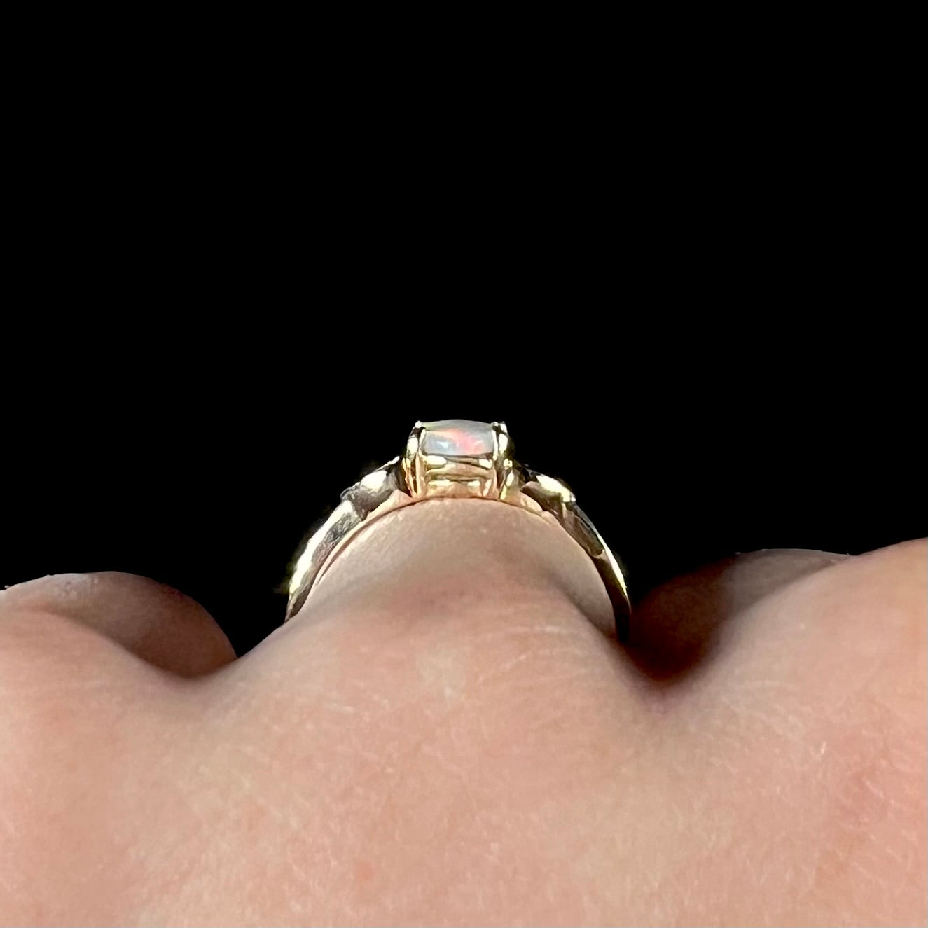 A dainty yellow gold ring mounted with a vivdly bright red Australian opal. The ring has two heart shaped designs.