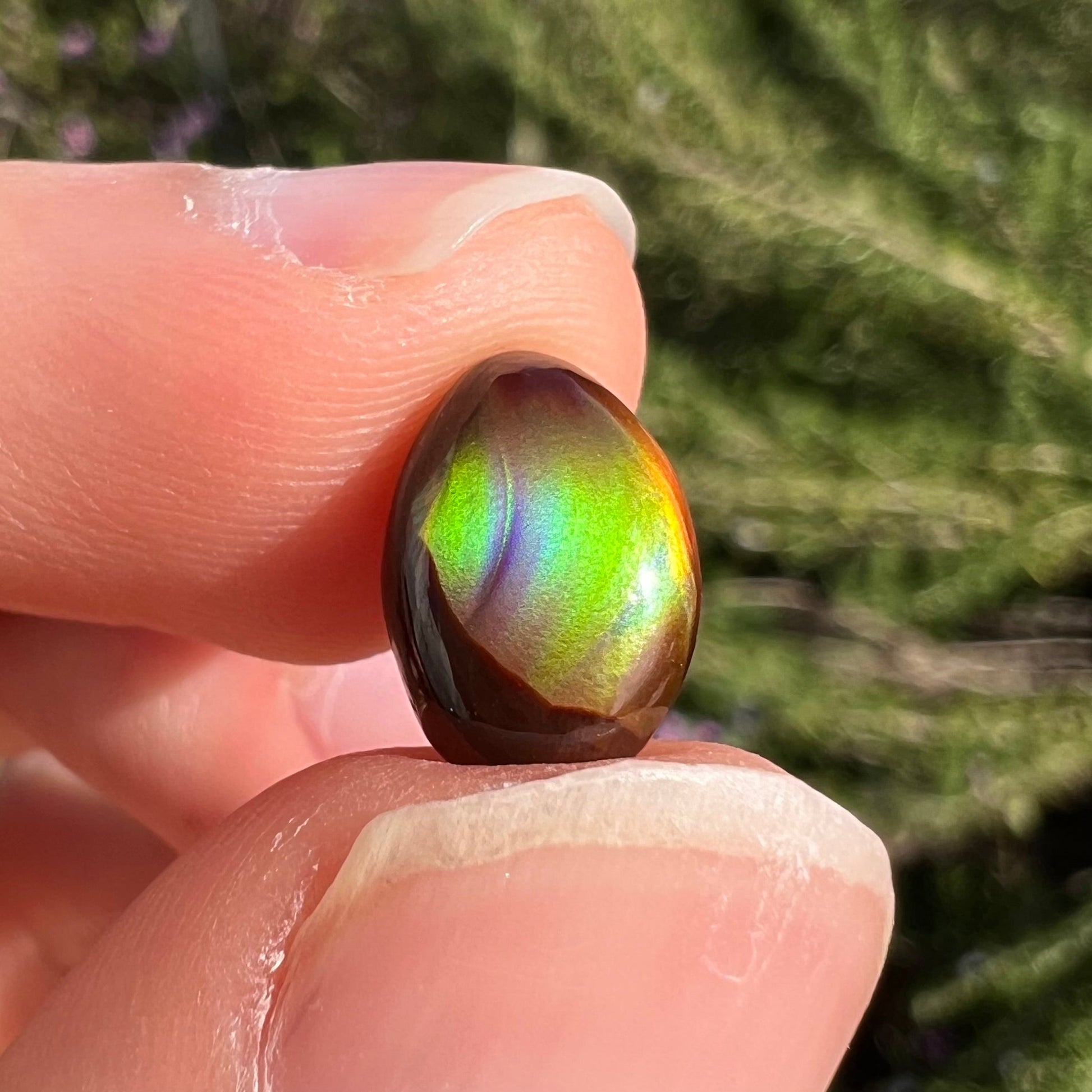 A loose, 3.38ct, pear shaped Mexican fire agate stone.  The stone shines a vivid, bright green color with a purple streak.