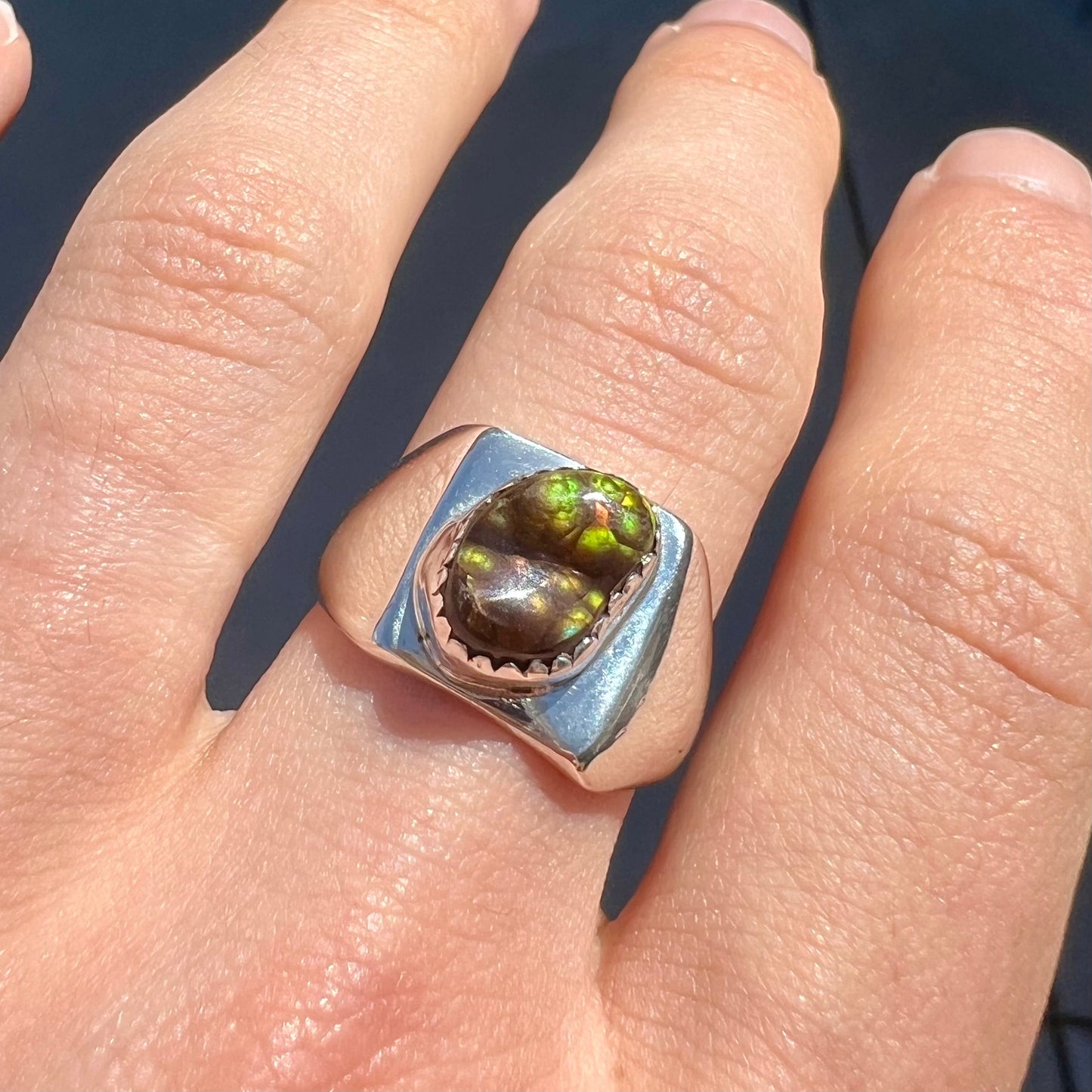 A unisex sterling silver solitaire ring bezel-set with a freeform Mexican fire agate cabochon. The stone is green and pink.