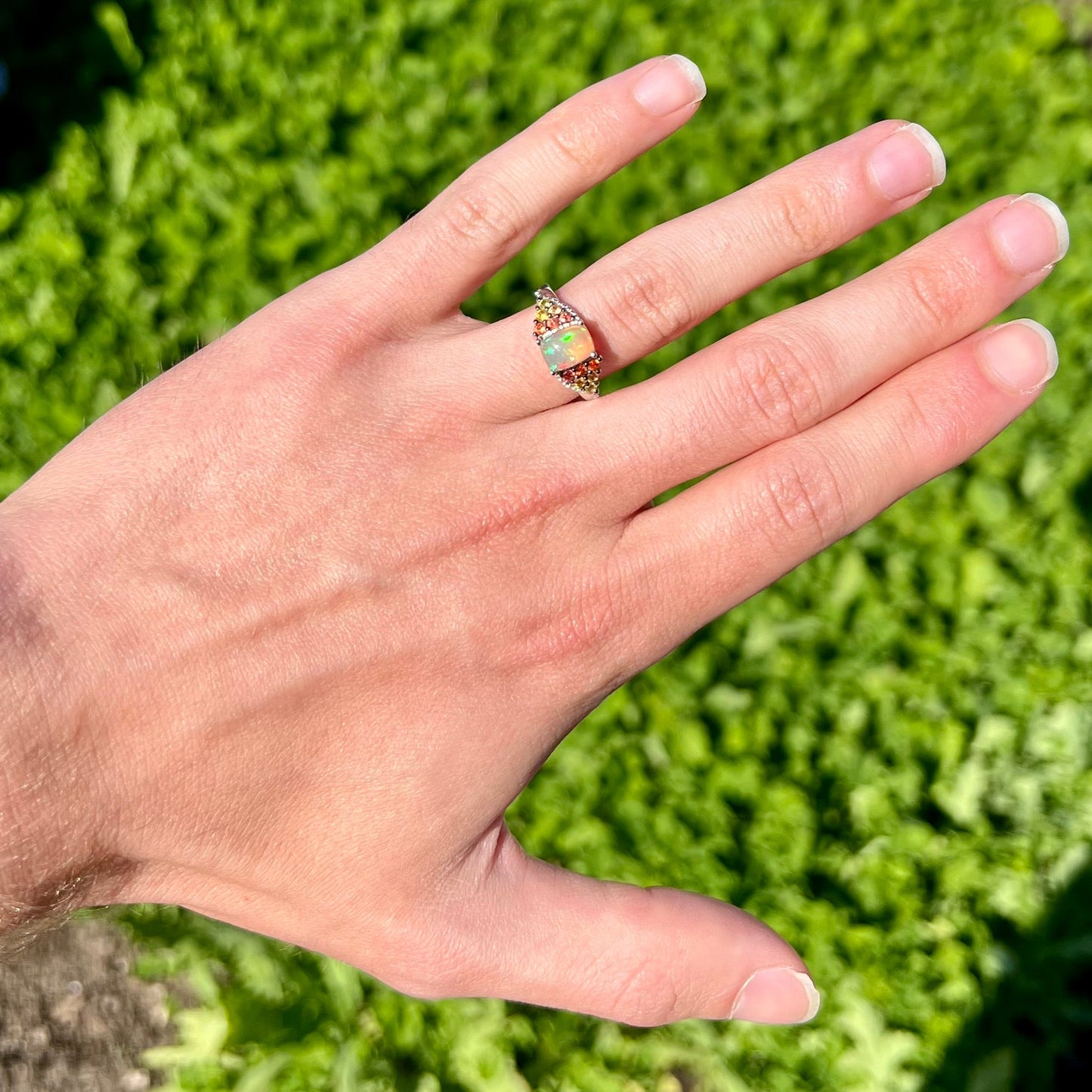 A ladies' silver ring set with a cushion cabochon cut Ethiopian fire opal stone and citrine accents.