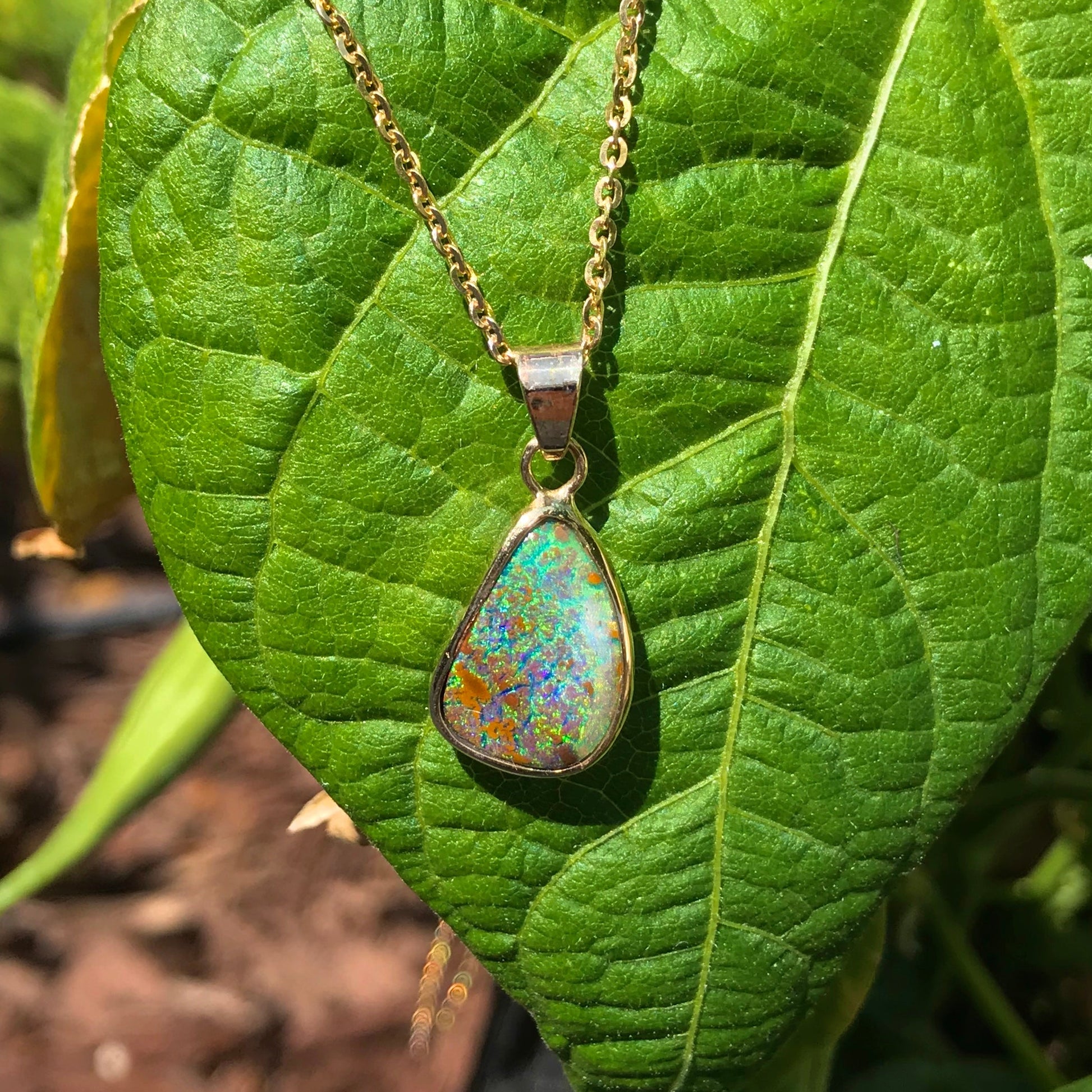 Green and blue Queensland boulder opal pendant in 14k yellow gold on cable chain.