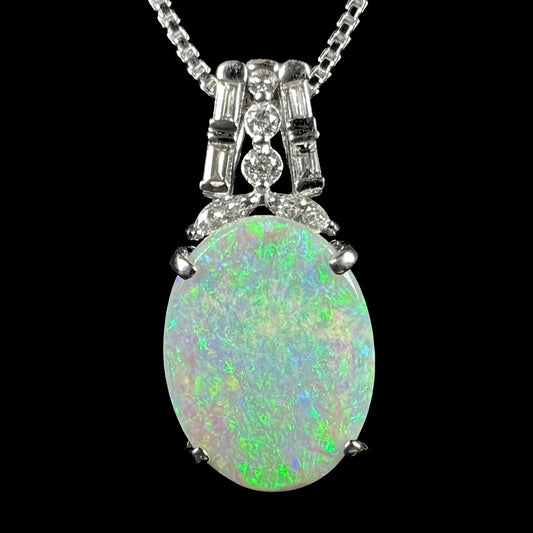 A macro view of the Kasumi dark opal and diamond pendant against a black background, showcasing its soft green color play.
