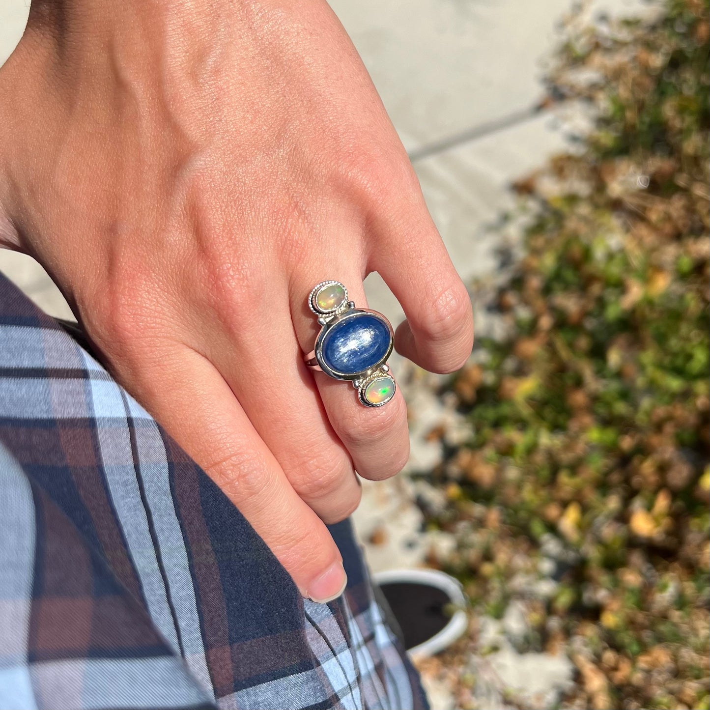 A hand resting on a person's hip while wearing an adularescent kyanite opal ring.