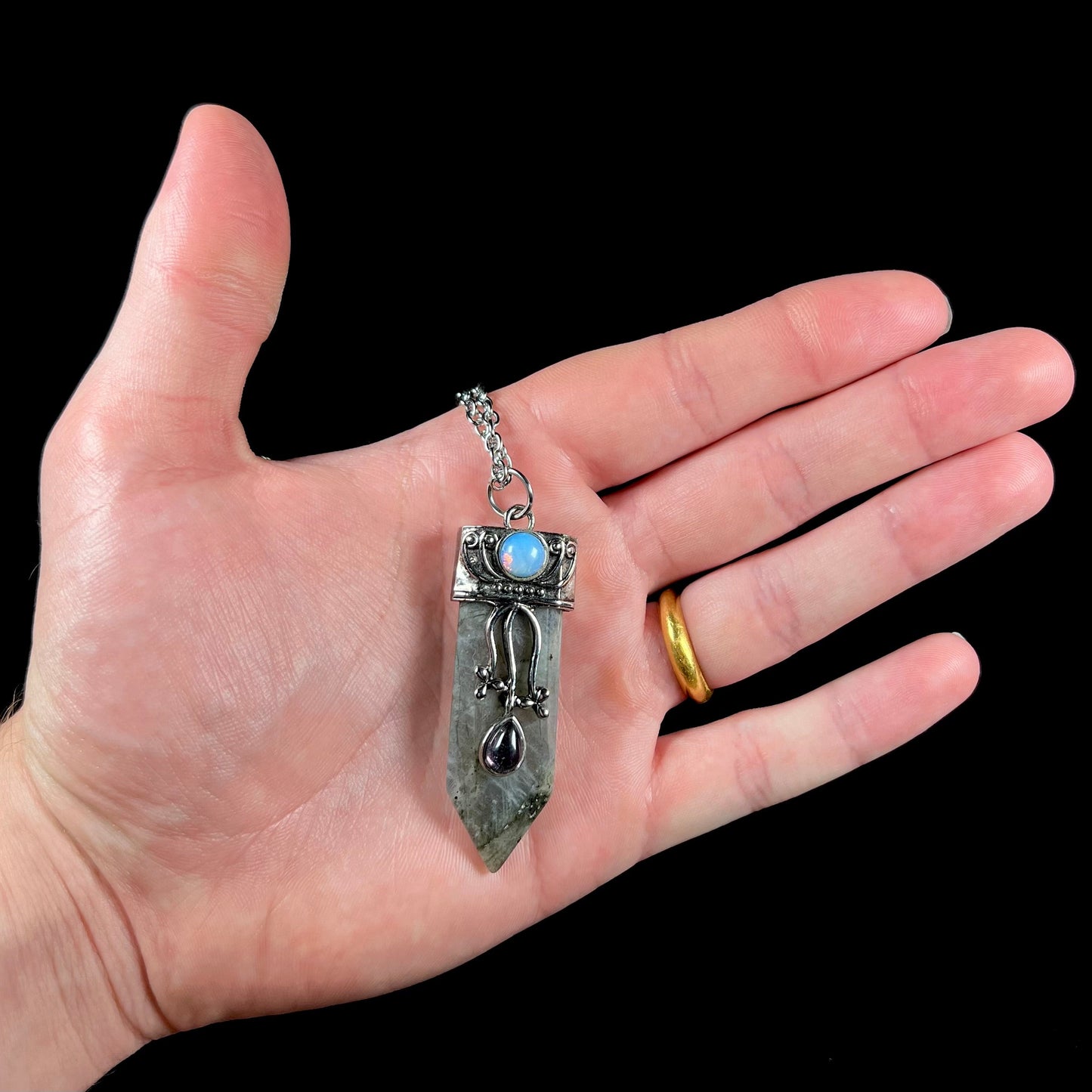 A stainless steal necklace set with a crystal shaped labradorite stone, purple glass, and an opalite accent.
