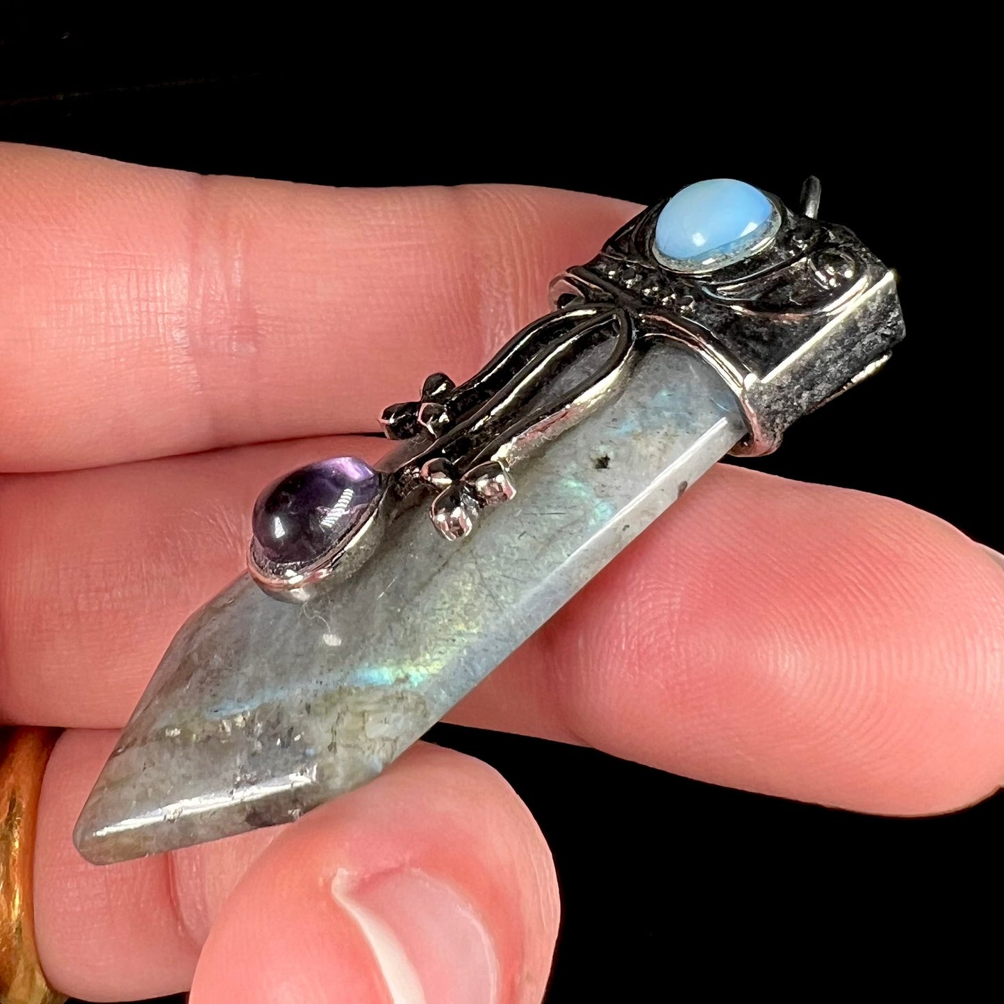 A stainless steal necklace set with a crystal shaped labradorite stone, purple glass, and an opalite accent.