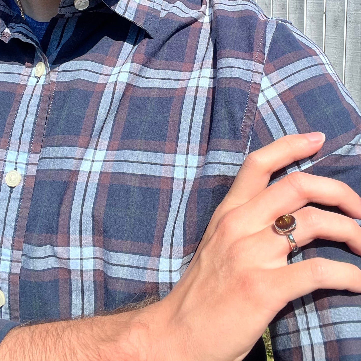 Person crossing arm and resting hand on opposing shoulder, wearing a ladies' silver fire agate ring.