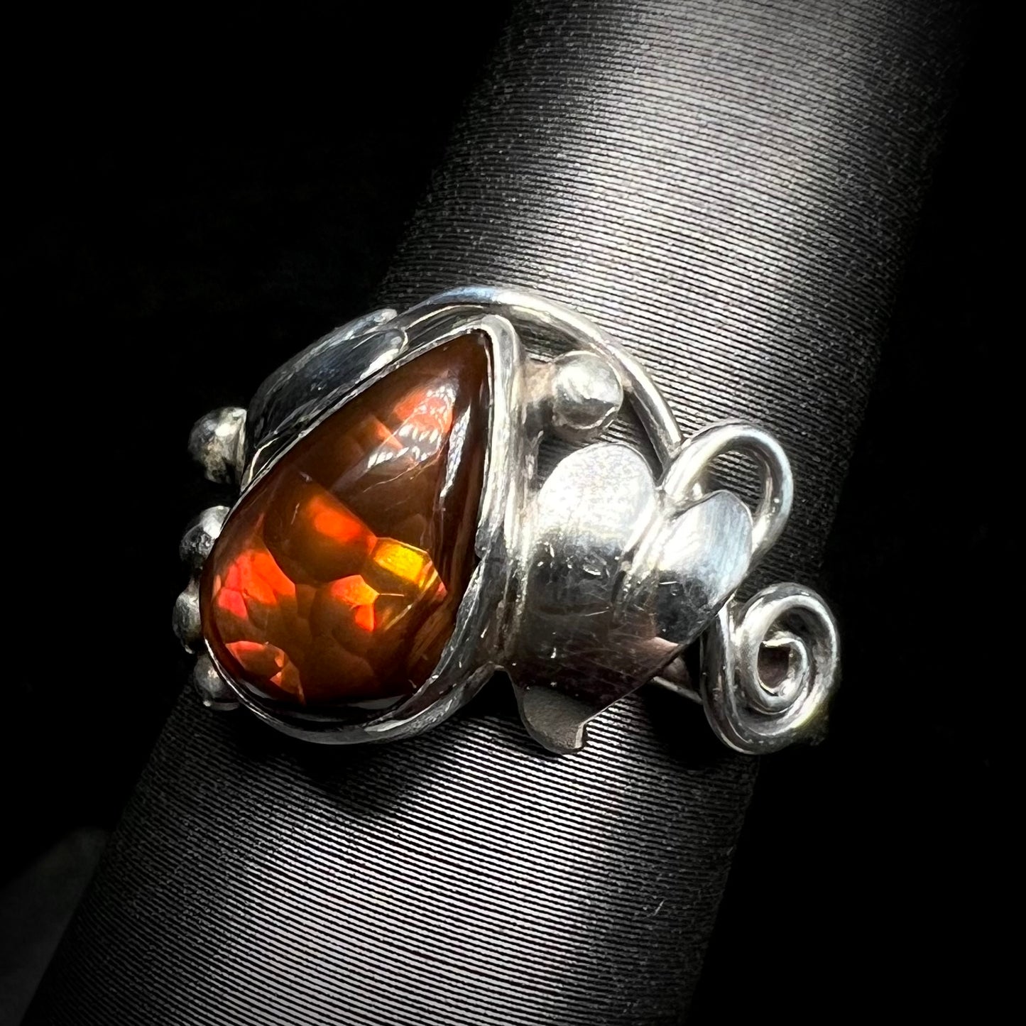 A ladies' pear shaped red fire agate ring with a sterling silver leaf design shown from an angle.