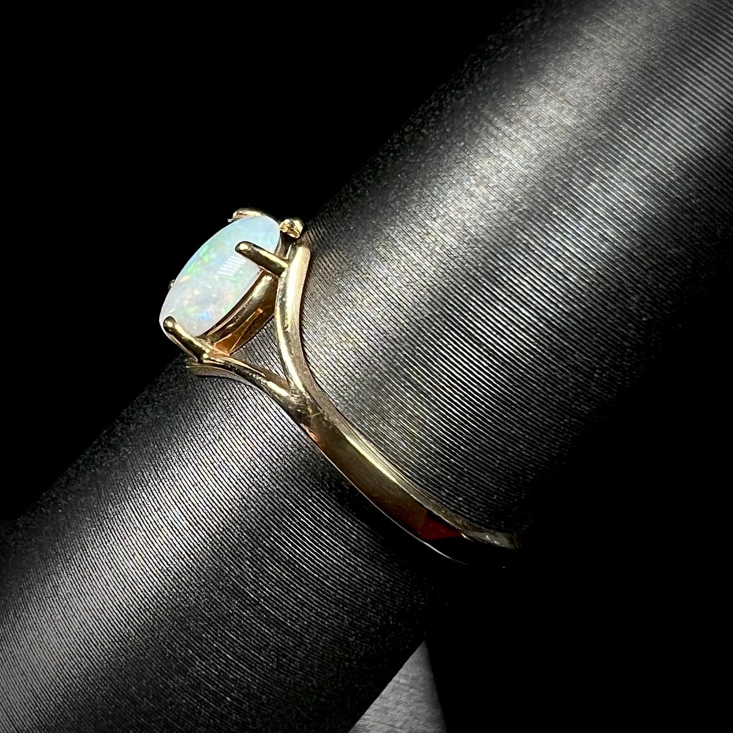A ladies' simple opal solitaire ring. The ring is yellow gold with a split shank.