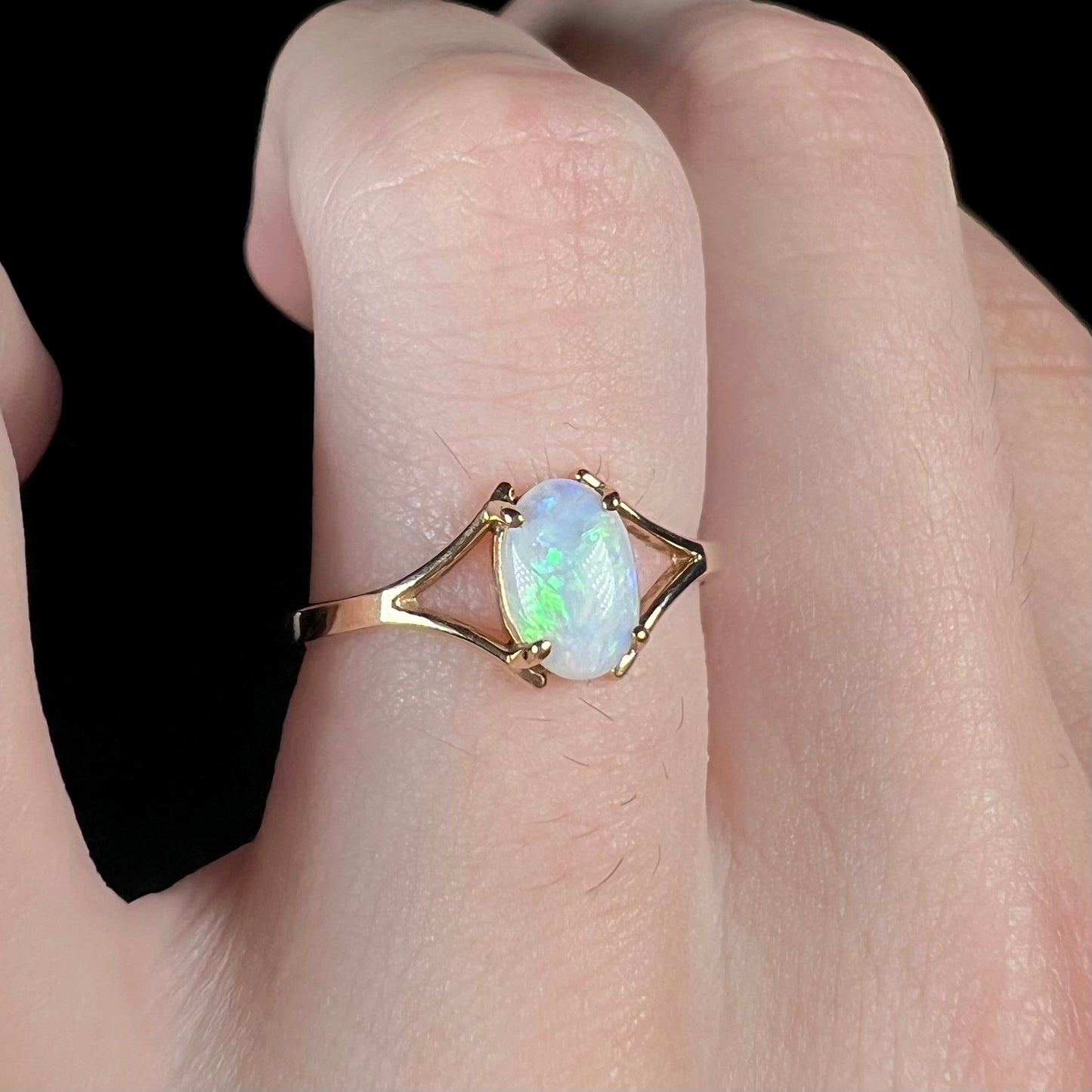 A ladies' simple opal solitaire ring. The ring is yellow gold with a split shank.