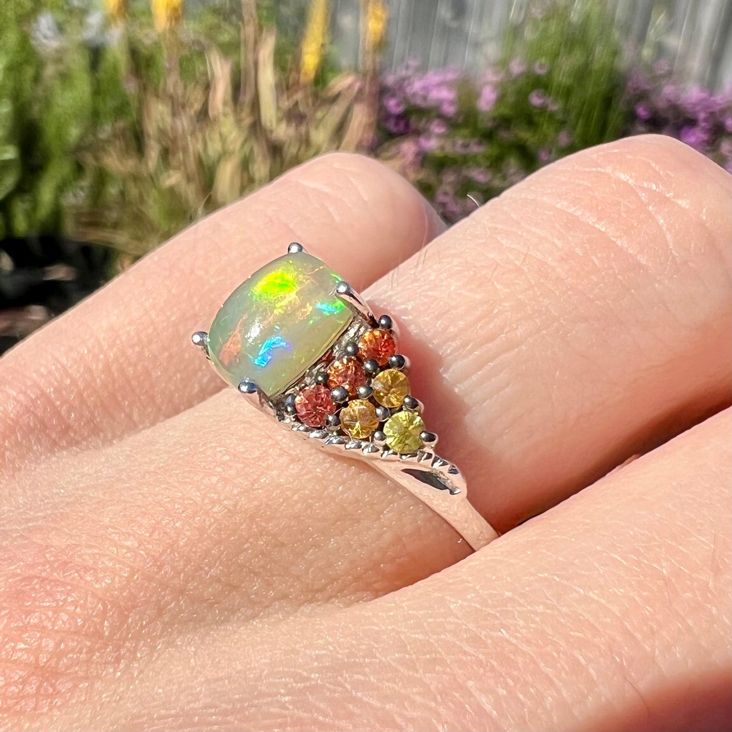 A ladies' silver ring set with a cushion cabochon cut Ethiopian fire opal stone and citrine accents.