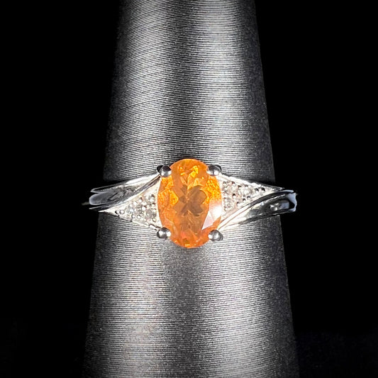 A sterling silver ladies' ring set with a faceted oval cut Mexican fire opal and round white zircon accent stones.