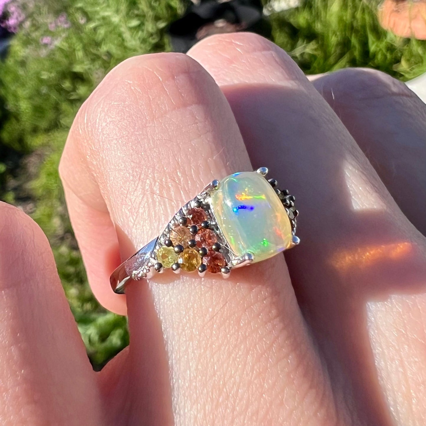 A ladies' silver ring set with a cushion cabochon cut Ethiopian fire opal stone and citrine accents.