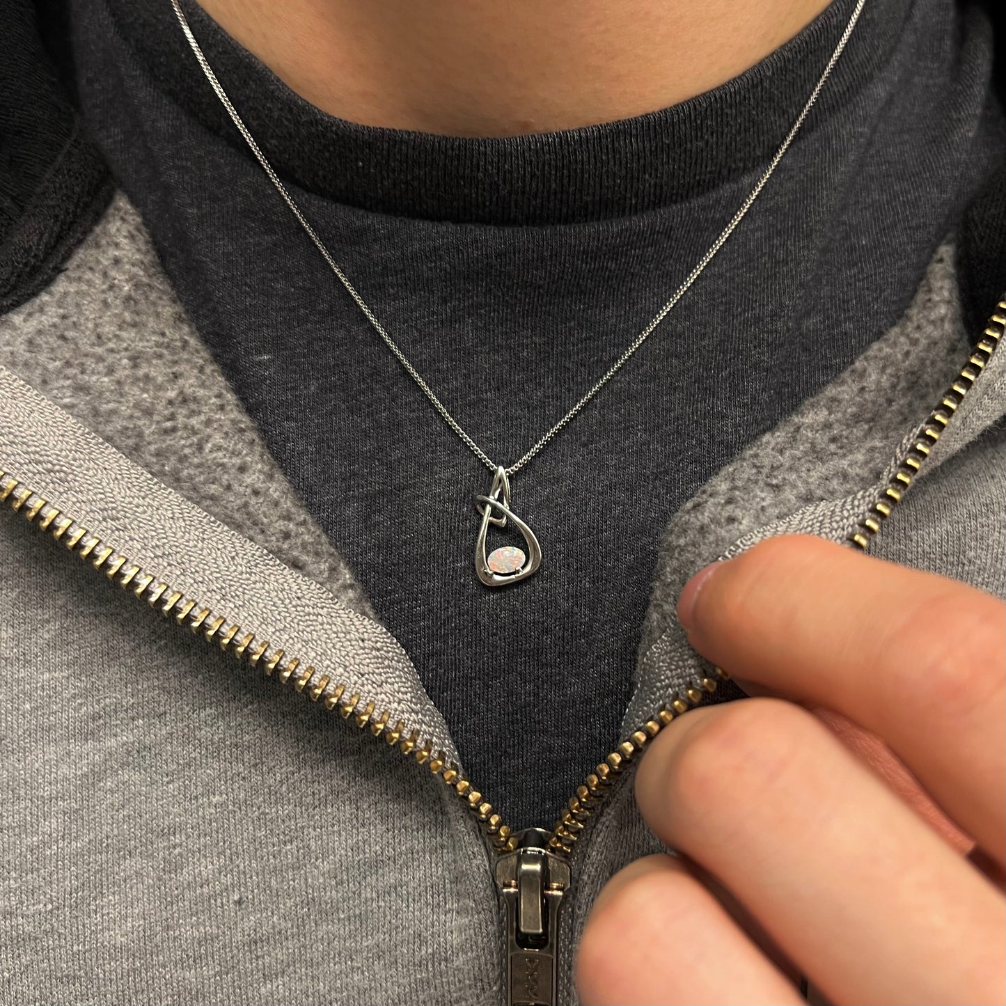A ladies' sterling silver pendant set with an oval cabochon cut natural white crystal opal.