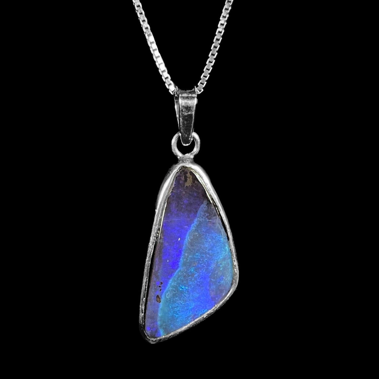 A ladies' sterling silver necklace bezel set with a triangle drop shaped Australian black boulder opal.