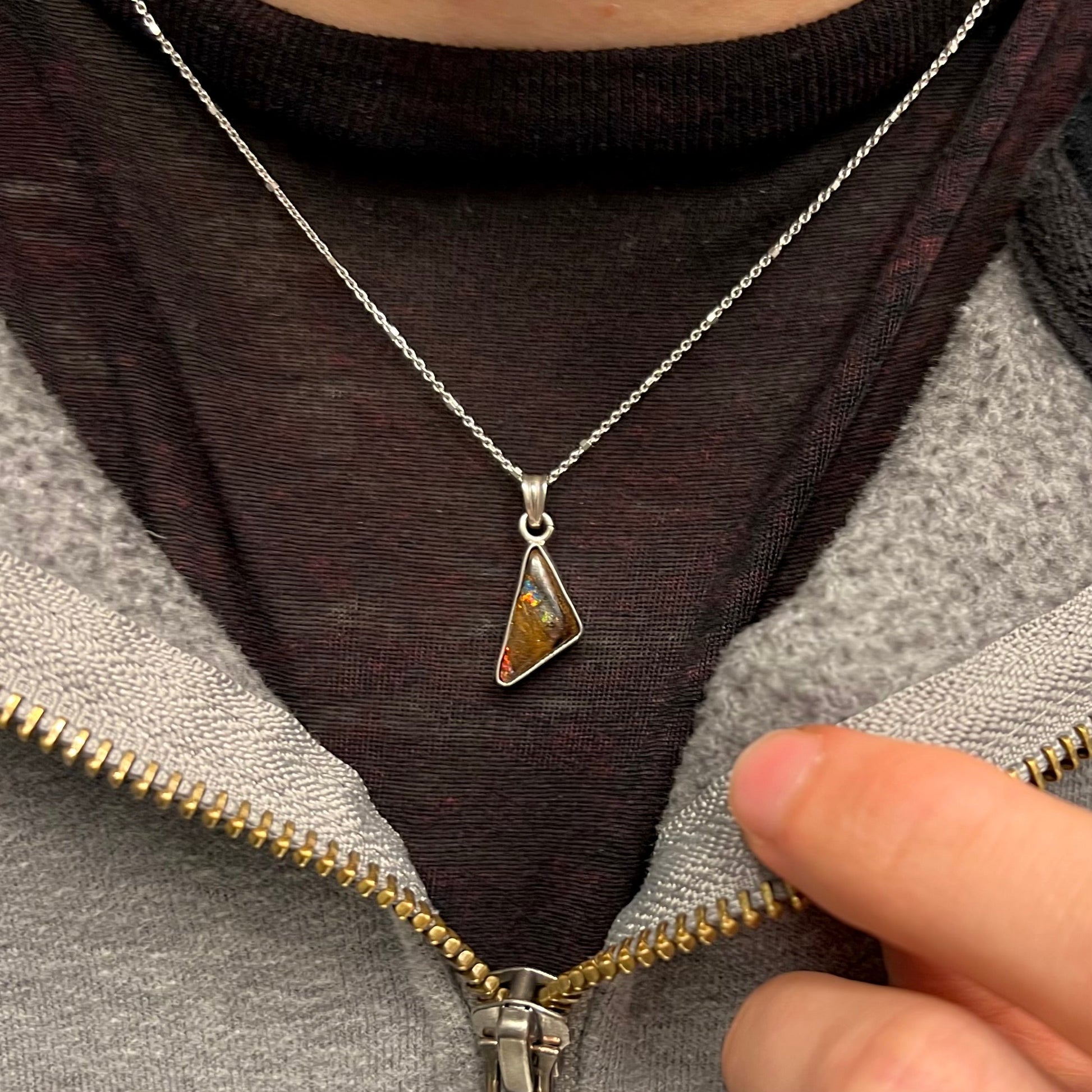 A triangle shaped opal necklace in sterling silver.  The opal shines with every color of the rainbow.