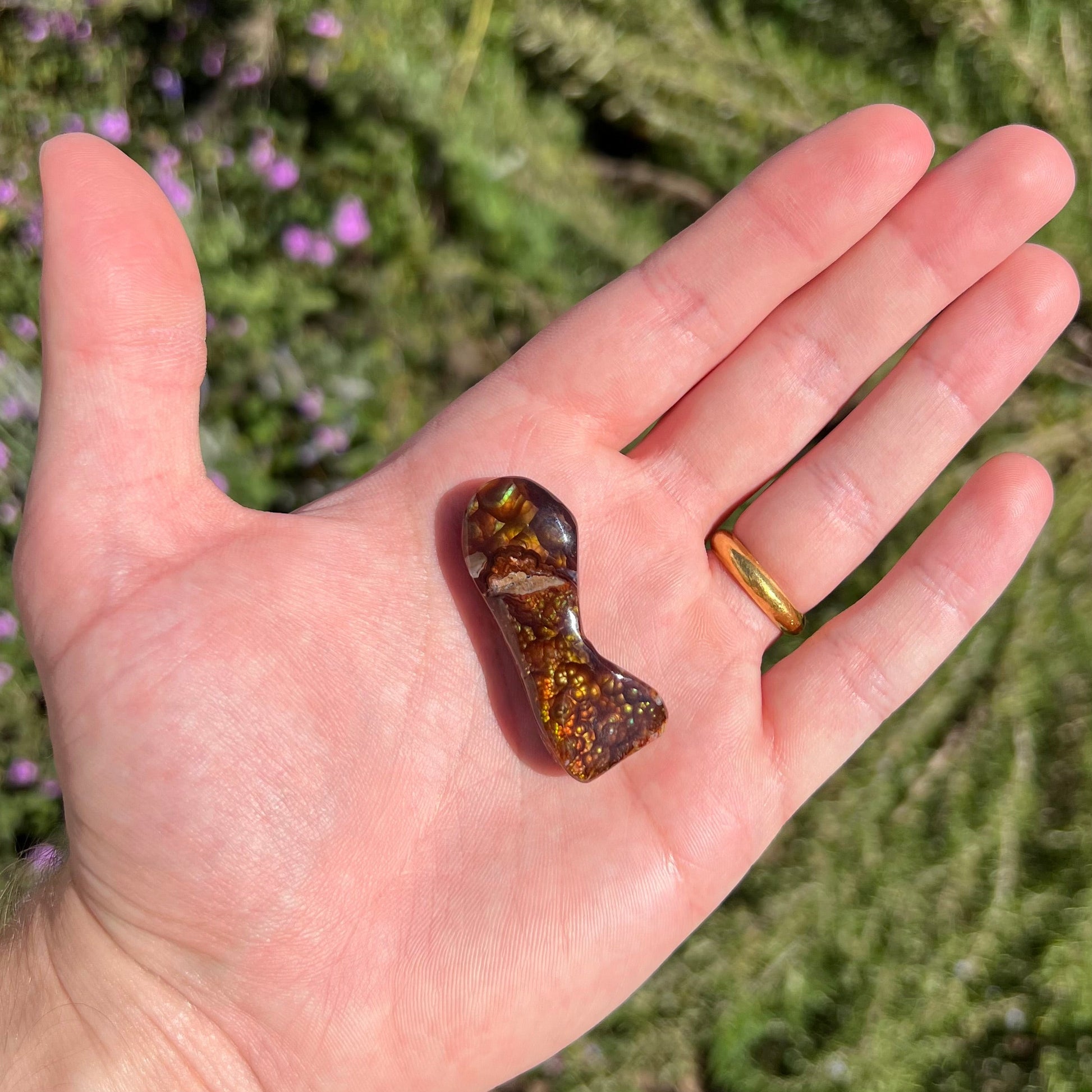 A loose, freeform cabochon cut fire agate gemstone.  The stone exhibits a bubbly pattern.