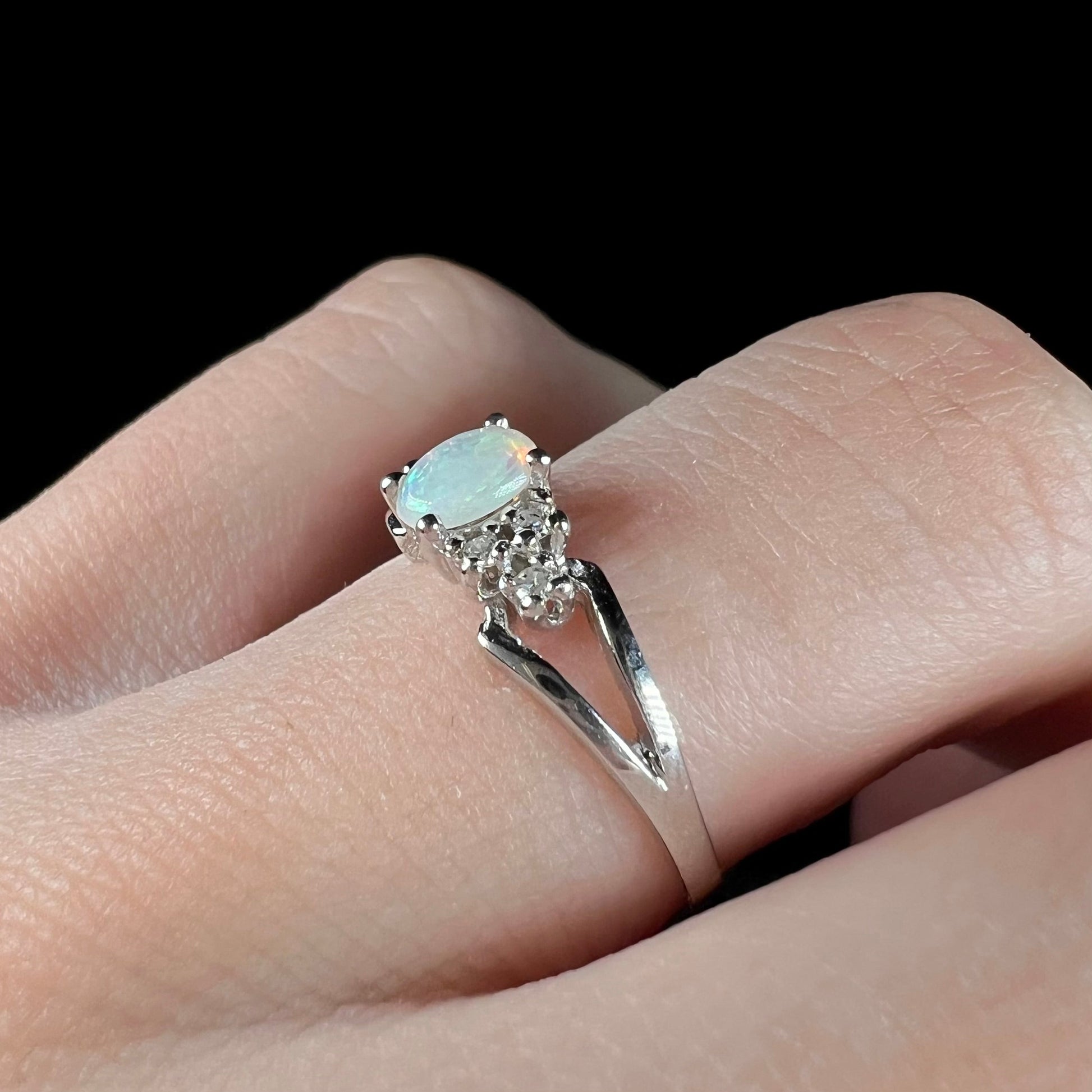A ladies' white gold opal ring mounted with round diamond accents.