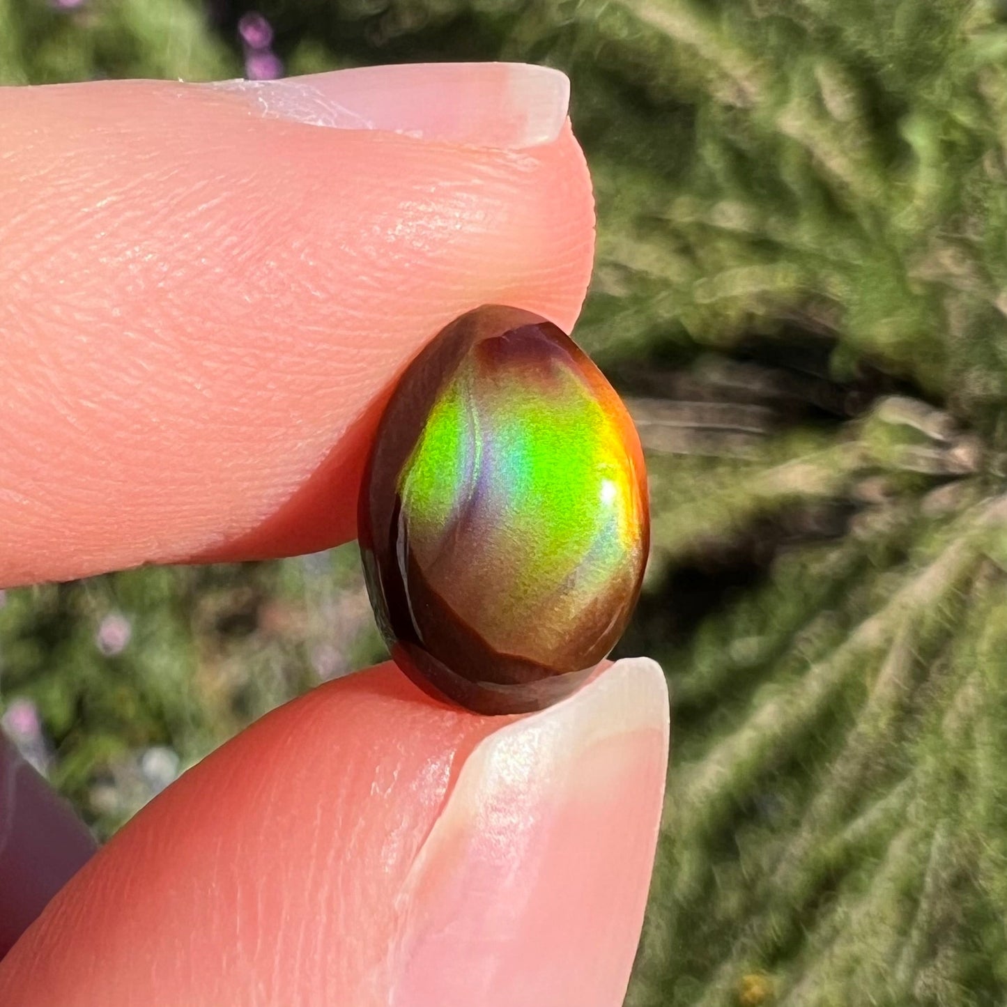A loose, 3.38ct, pear shaped Mexican fire agate stone. The stone shines a vivid, bright green color with a purple streak.
