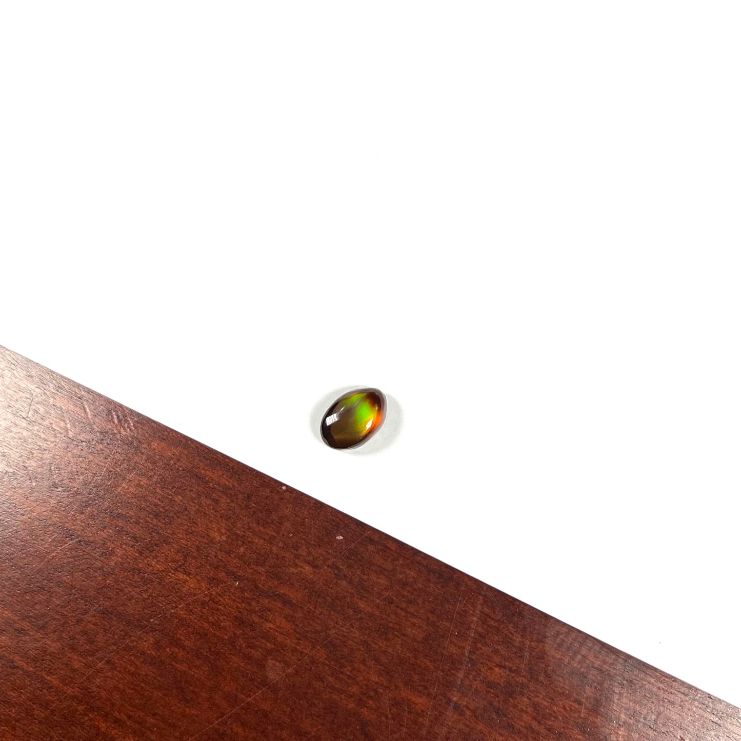 A loose, 3.38ct, pear shaped Mexican fire agate stone. The stone shines a vivid, bright green color with a purple streak.