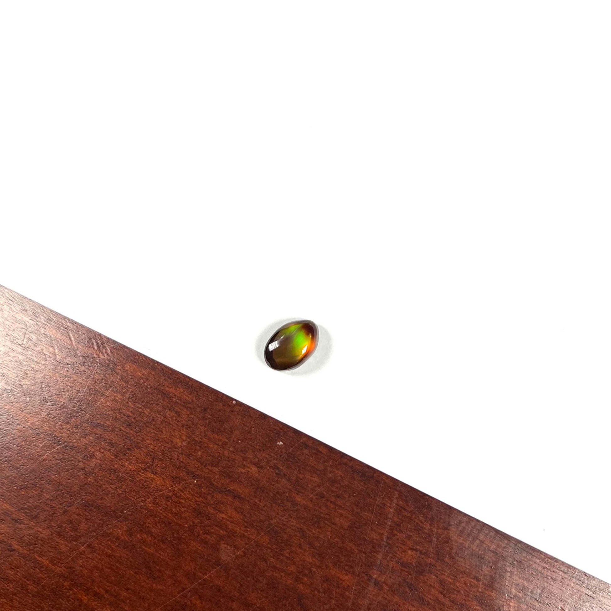 A loose, 3.38ct, pear shaped Mexican fire agate stone.  The stone shines a vivid, bright green color with a purple streak.