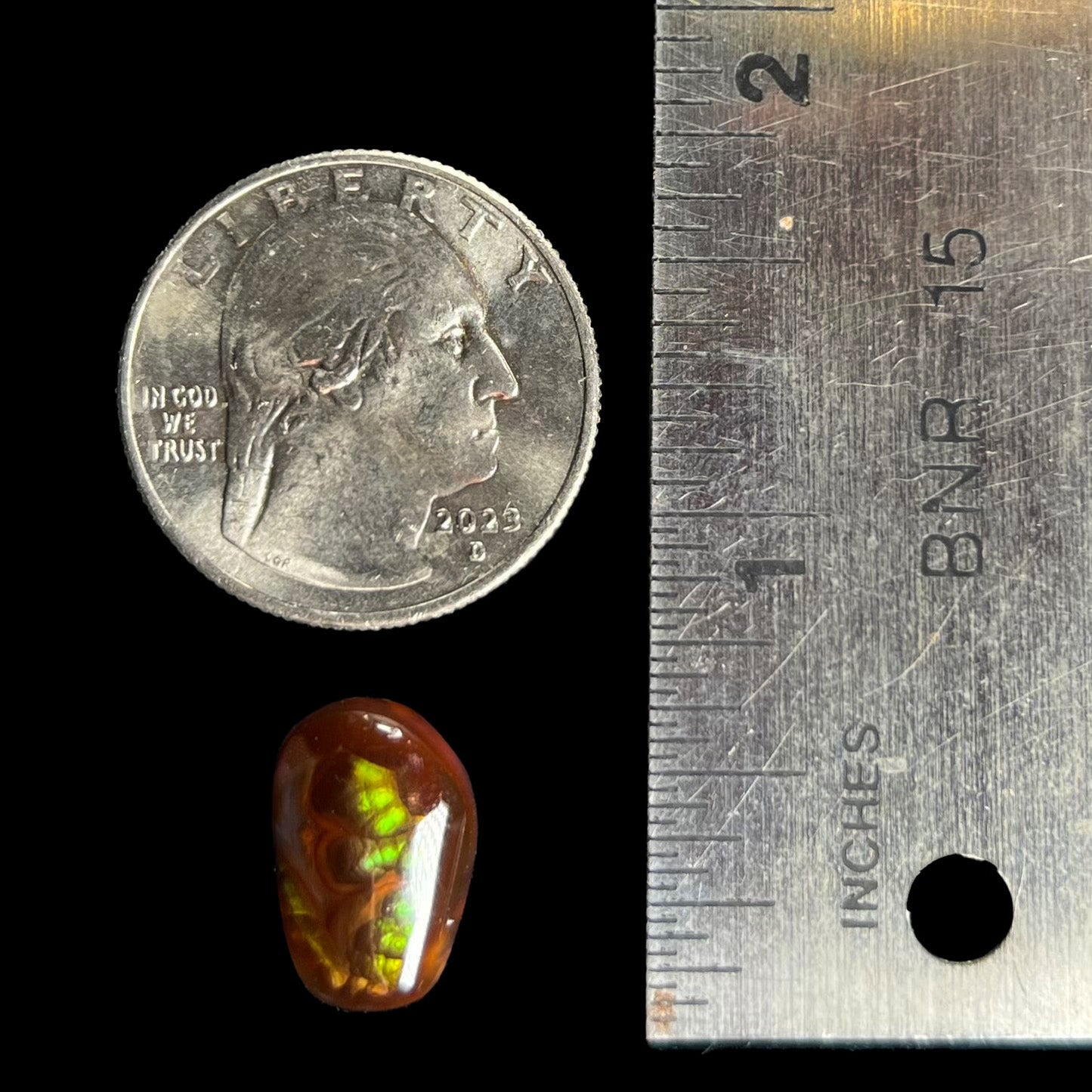 A loose, freeform cabochon cut fire agate gemstone. The stone is green with blue overtones.