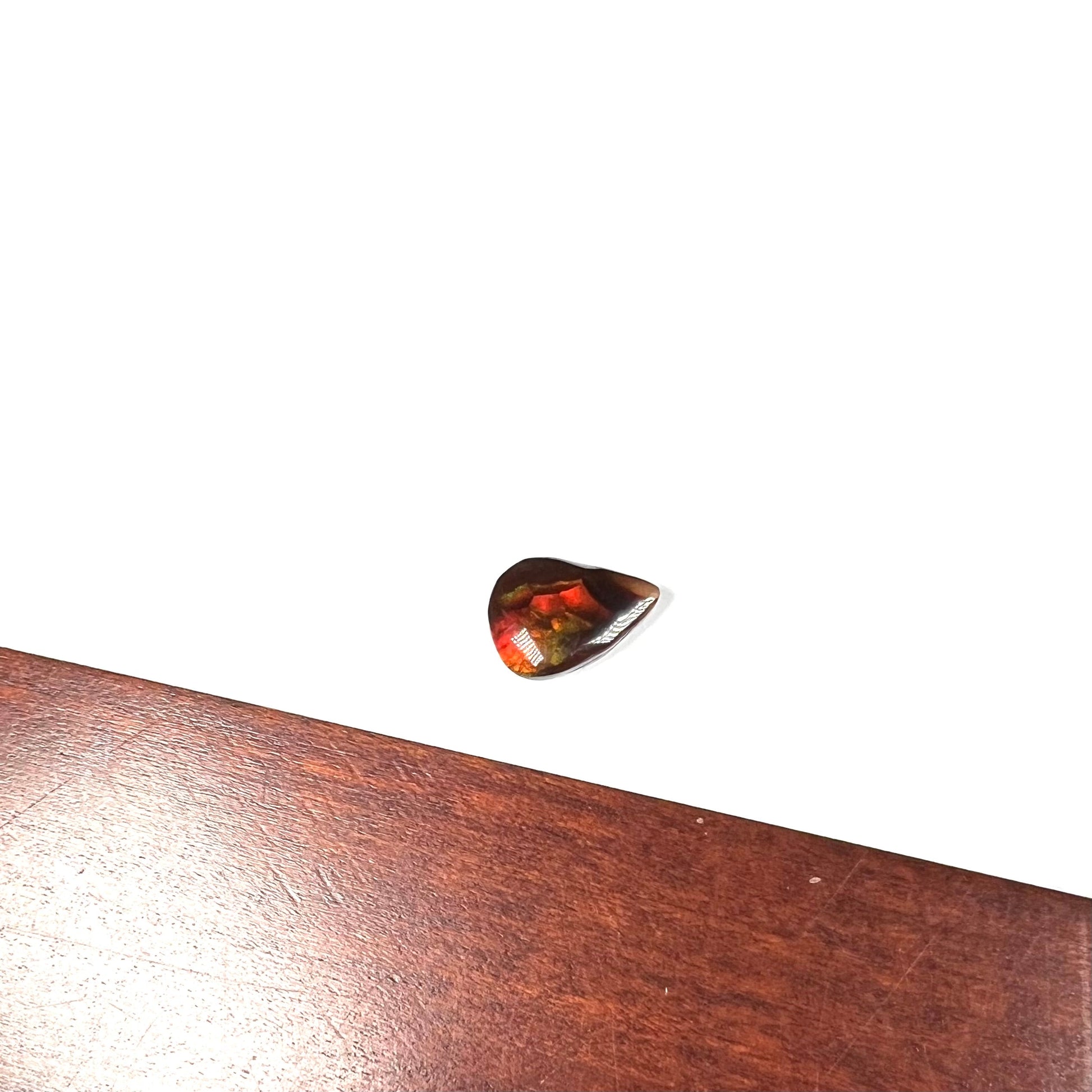 A loose, pear shaped Mexican fire agate gemstone.  The stone is predominantly vivid red with green overtones.