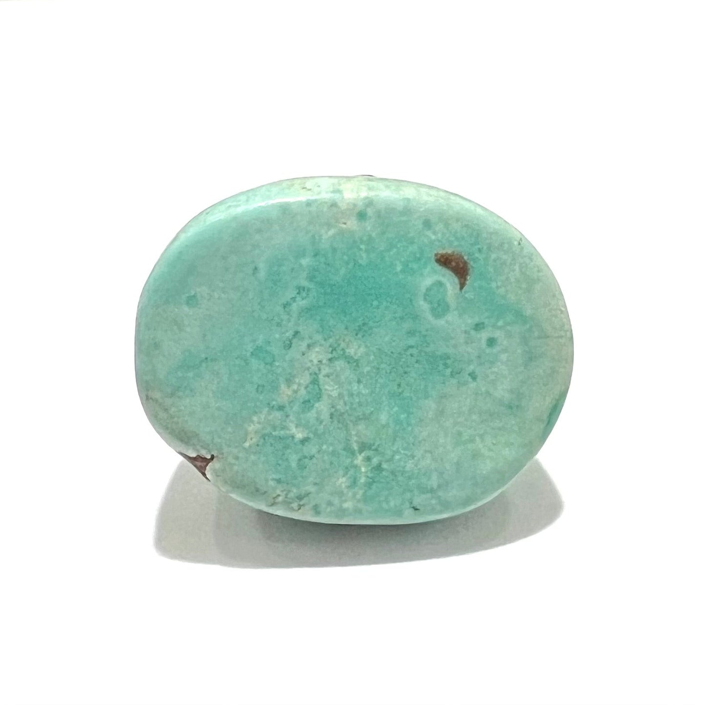 A loose, oval cabochon cut turquoise stone from the Sleeping Beauty Mine in Arizona. The stone is a greenish blue color.