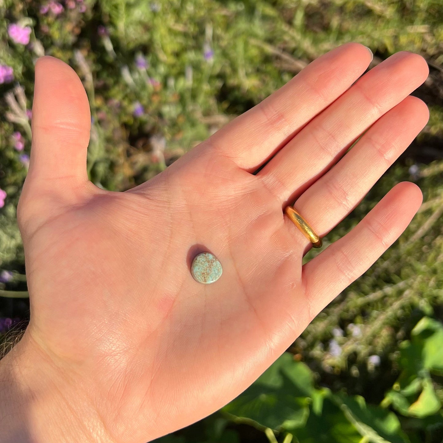 A loose, off-round cabochon cut turquoise stone. The stone is light blue with a red webbed matrix.