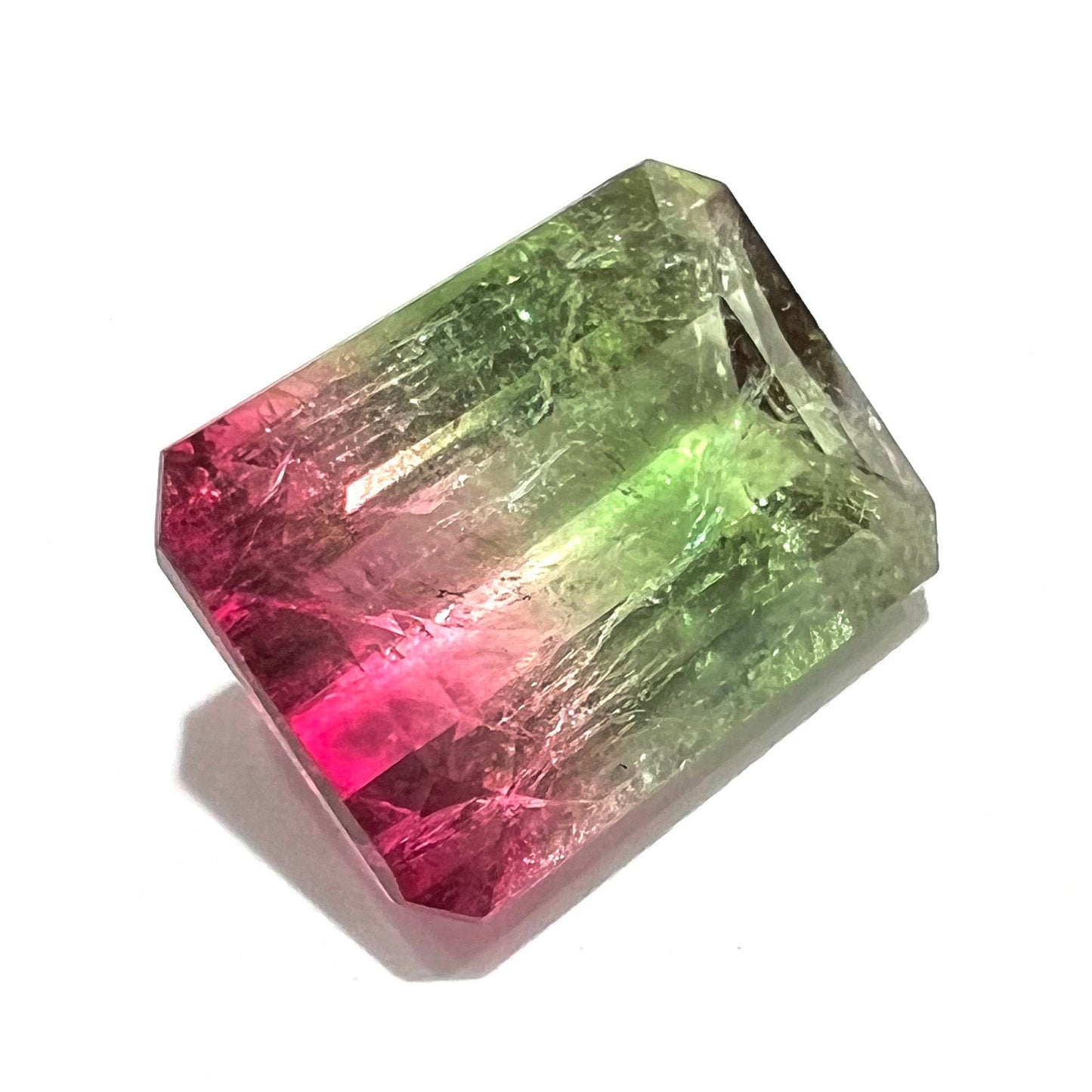 A loose watermelon tourmaline gemstone. The stone is emerald cut and fades from hot pink to green.