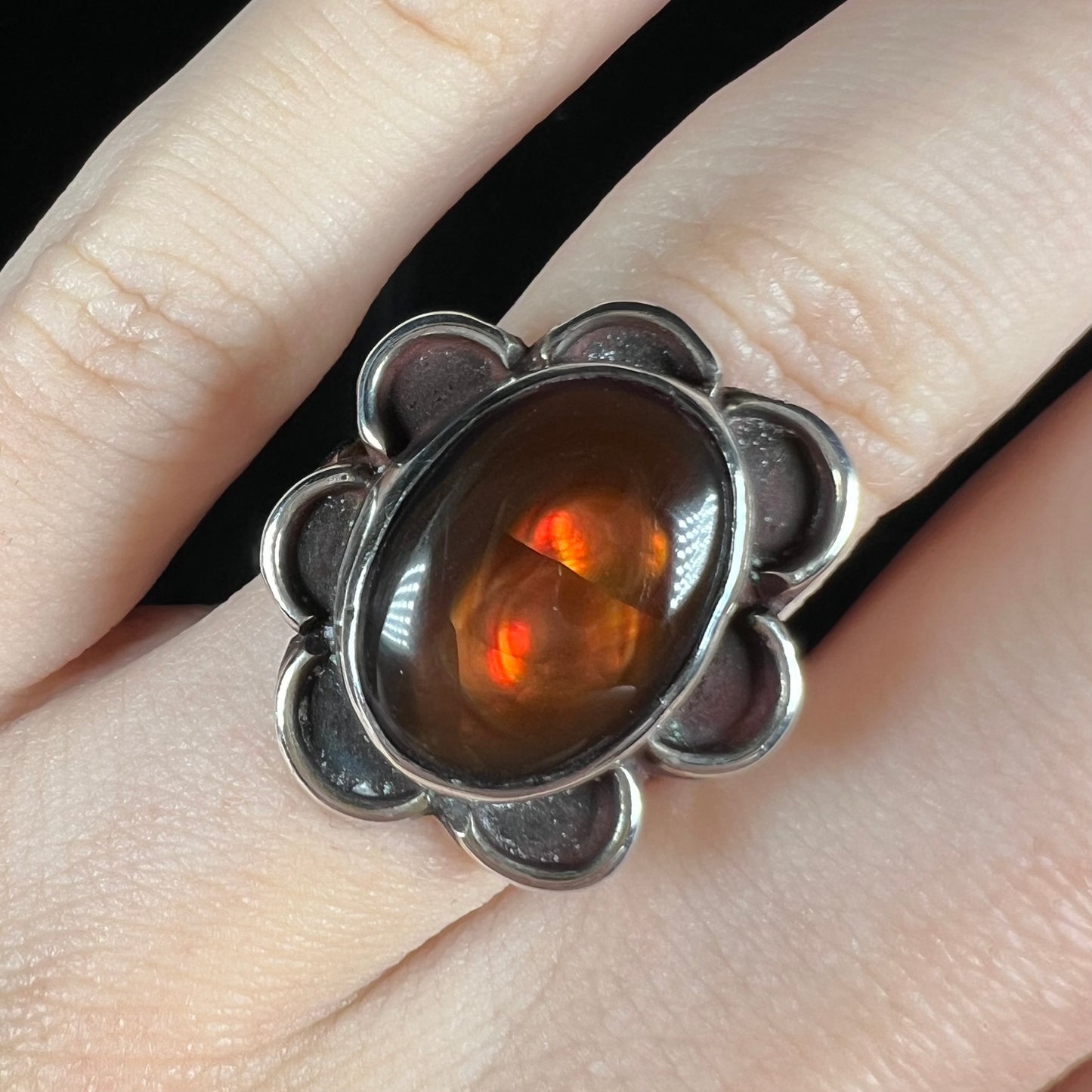 Macro of handmade fire agate ring worn, showing vivid red color play.