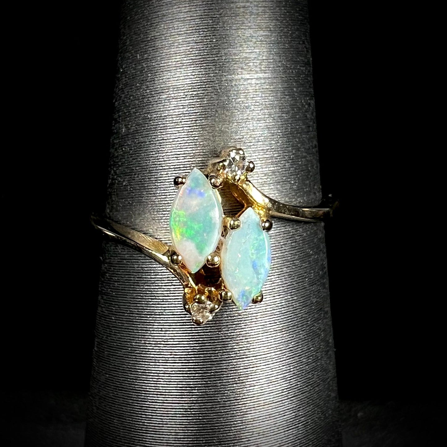 A ladies' gold ring mounted with two marquise cut opals and two diamond accents.