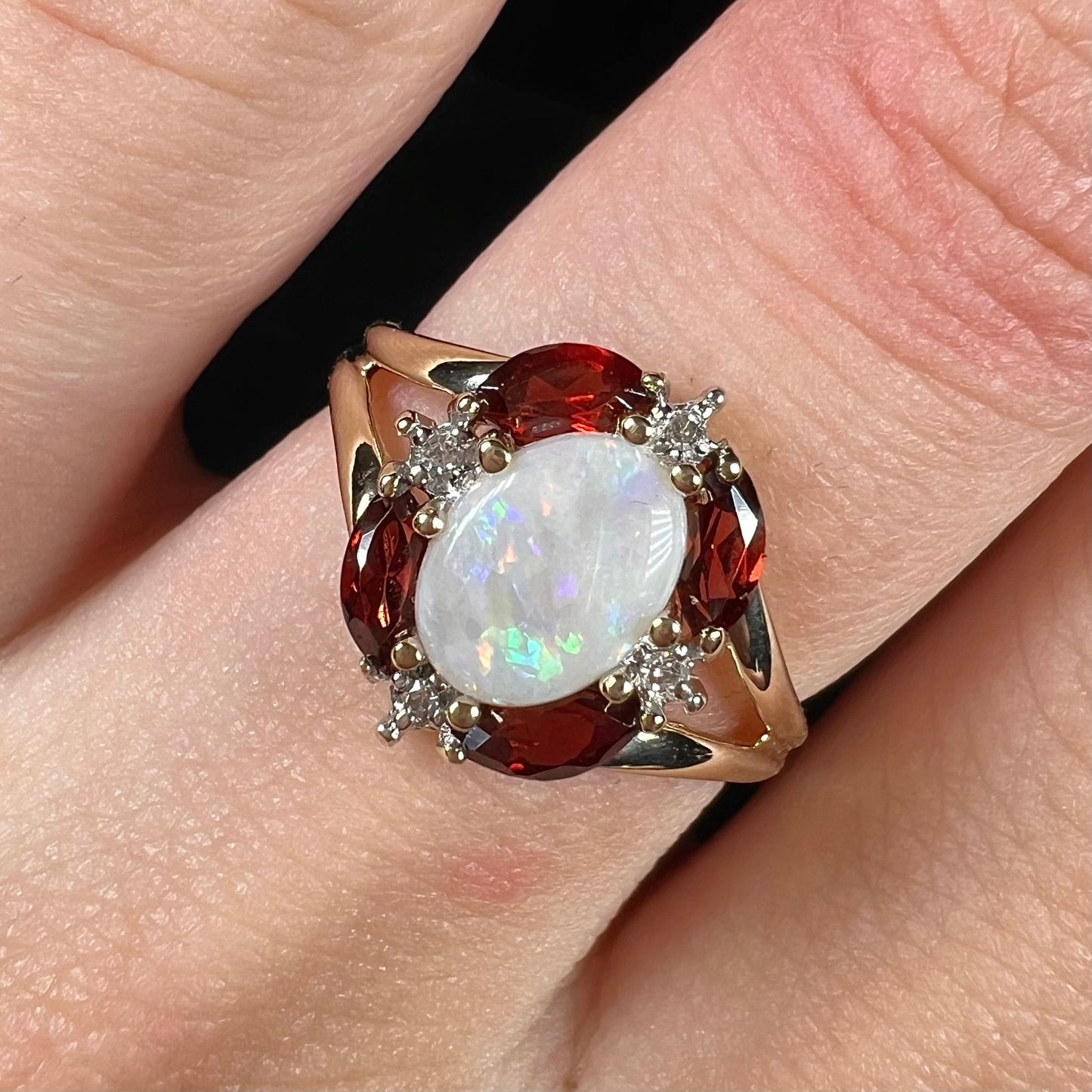 A ladies natural opal ring in yellow gold. The opal is surrounded by red marquise cut garnets and diamonds.
