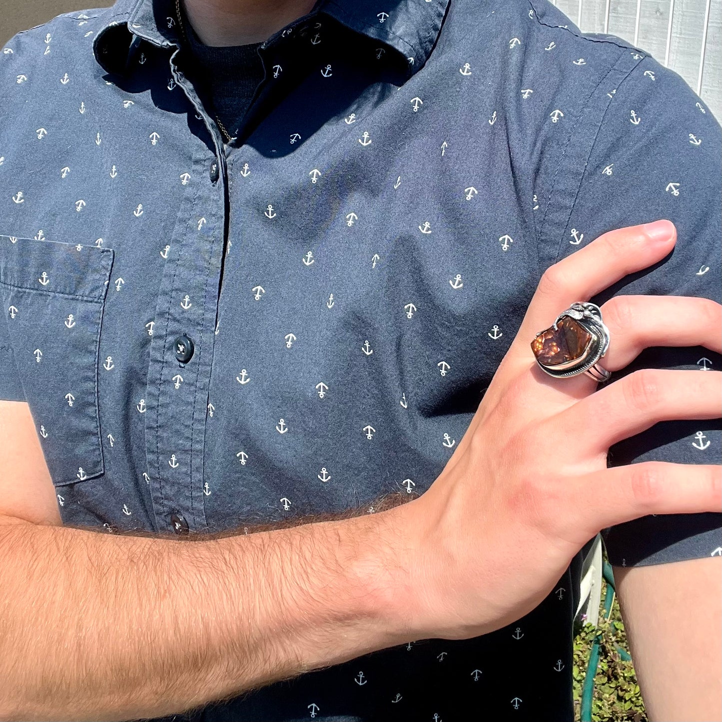 A men's silver, Southwest-style fire agate ring worn on a hand that's resting on the model's opposing shoulder.