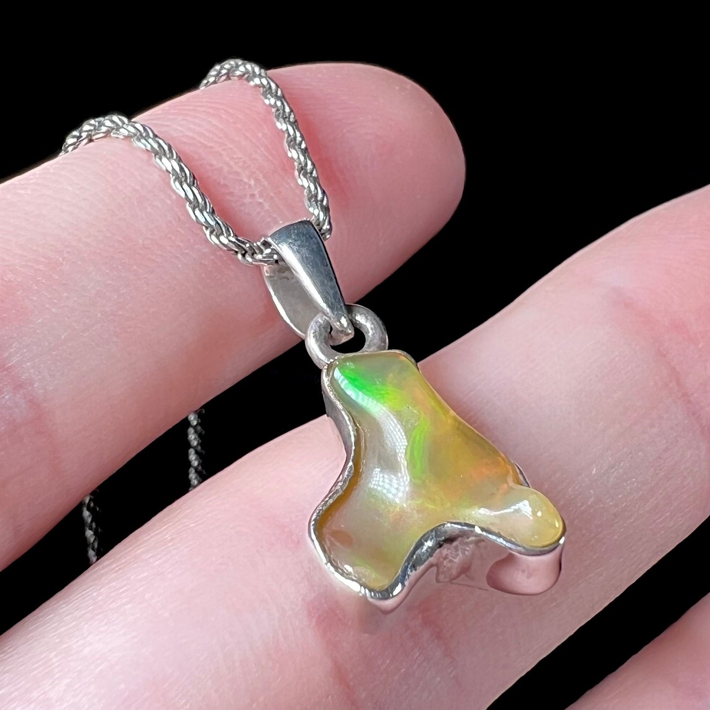 A freeform shaped Mexican fire opal necklace on a sterling silver rope chain.