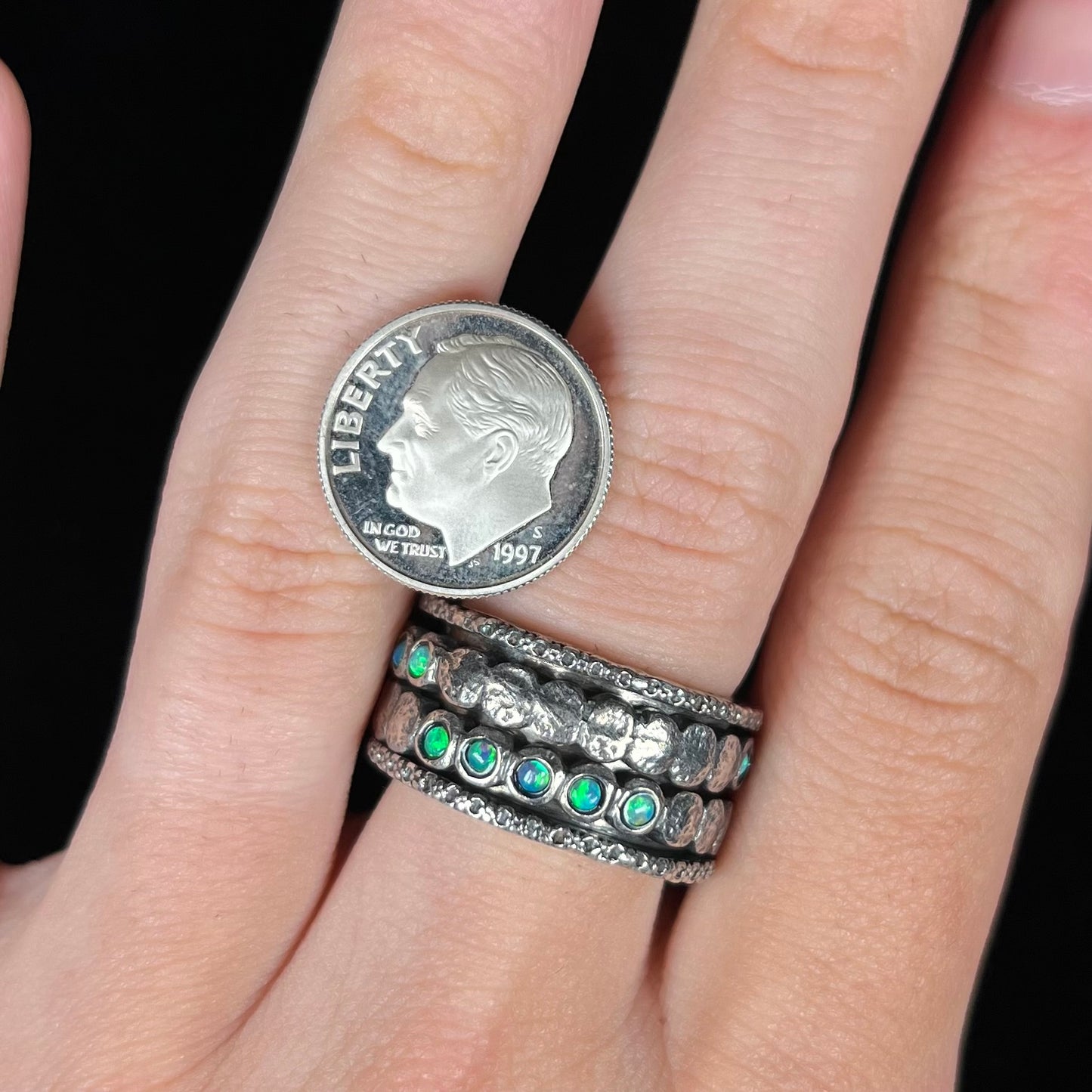 An 11.5mm wide men's opal spinner ring worn on a finger next to a dime coin for scale.