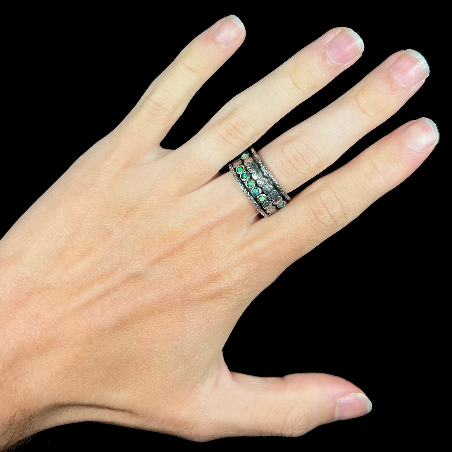 Hand wearing a men's opal spinner ring made from sterling silver.