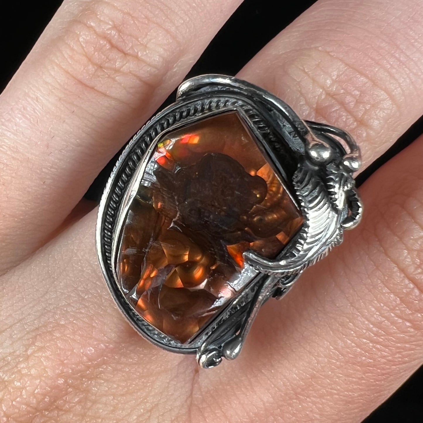 Close-up of a men's silver, Southwest-style fire agate ring worn on a finger.