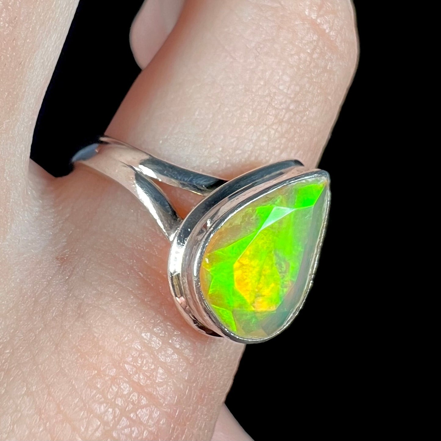 A unisex sterling silver ring set with a faceted pear shaped Ethiopian fire opal. The opal plays orange, red, and green colors.