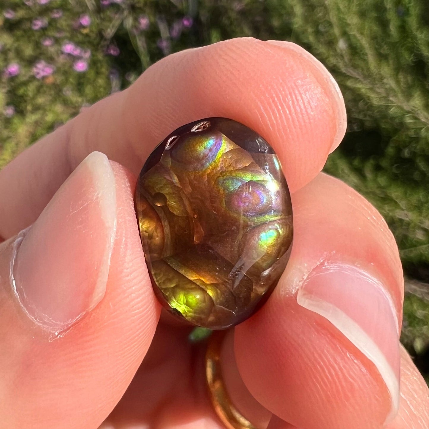 A loose, oval cabochon cut Mexican fire agate stone with pink, orange, and purple banding.