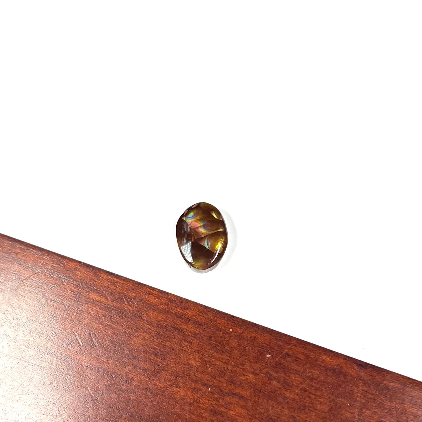 A loose, oval cabochon cut Mexican fire agate stone with pink, orange, and purple banding.